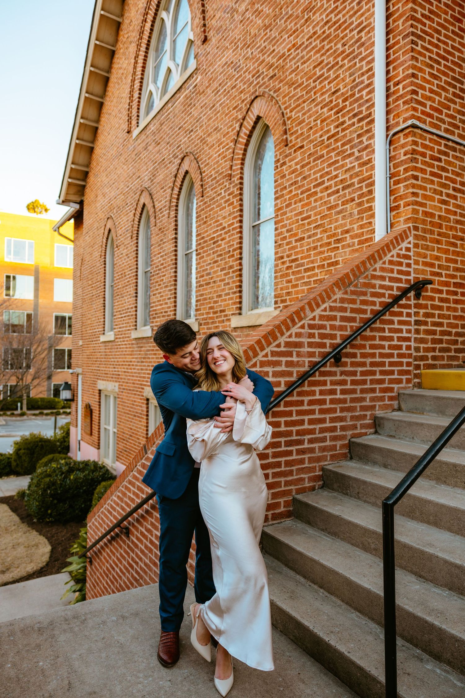 Romantic moment captured on brick church steps during winter wedding photoshoot.