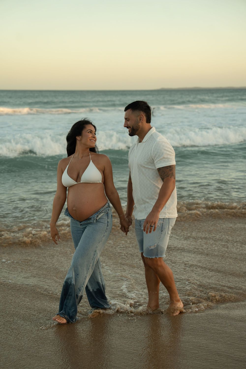 beach maternity photography, wearing jeans and in water.