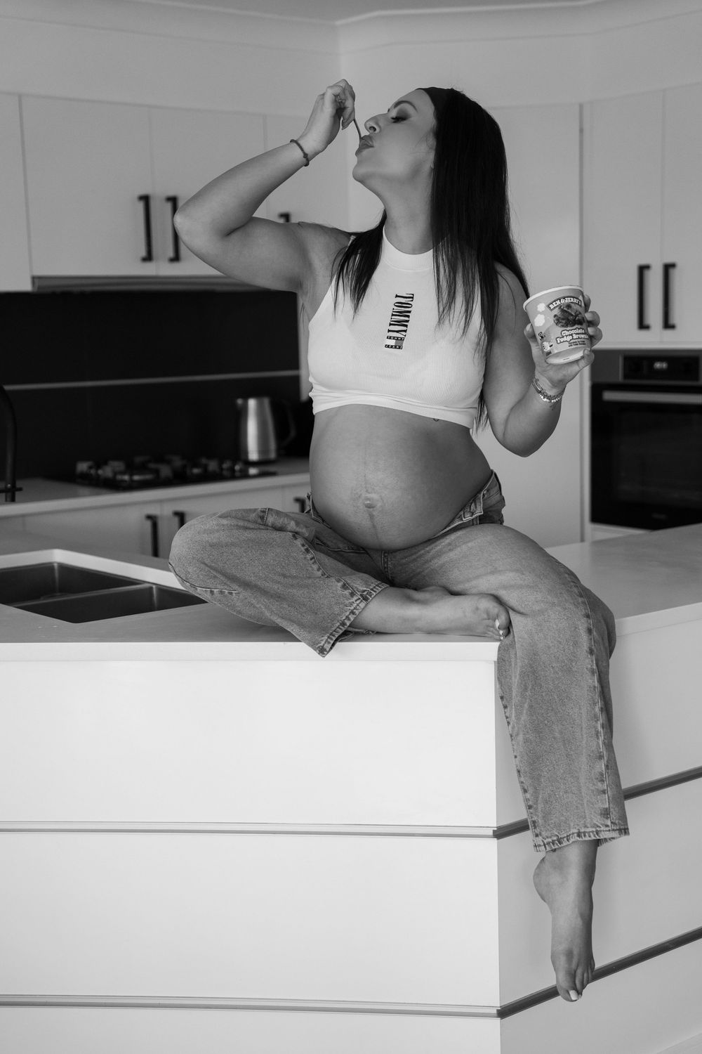Lifestyle maternity photography session in Wollongong of pregnant woman eating ice cream on kitchen bench