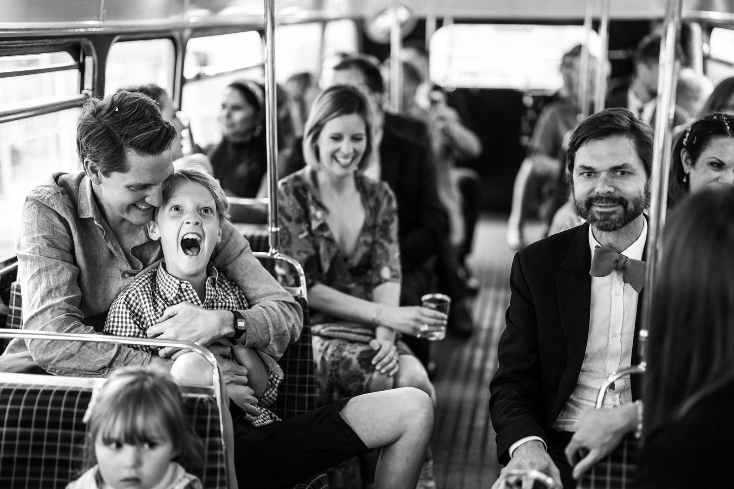 Black and white candid photo of passengers sharing a joyful moment while riding on public transportation.