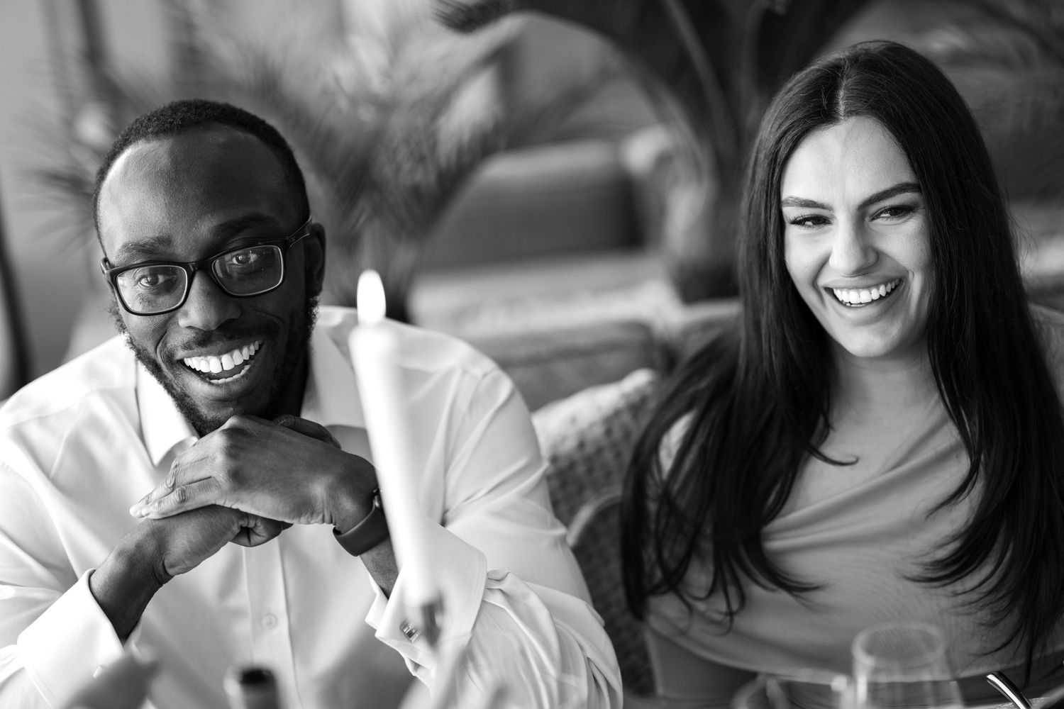 A black and white photo captures two professionals laughing together during a casual workplace meeting.