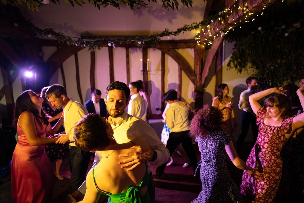 Couples dancing at a vibrant indoor party with colorful lighting and festive decorations.