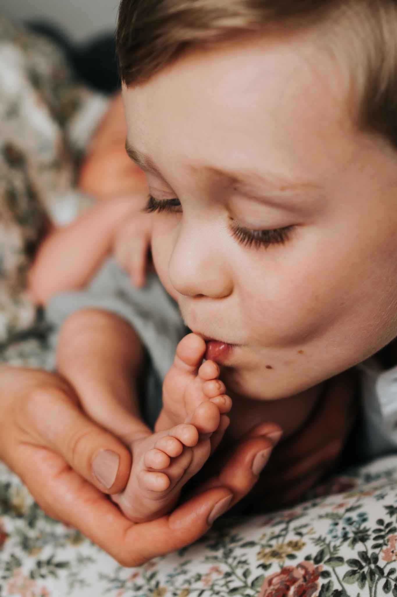 siostra, mama i tata trzymają w objęciach noworodka - sesja noworodkowa Kraków