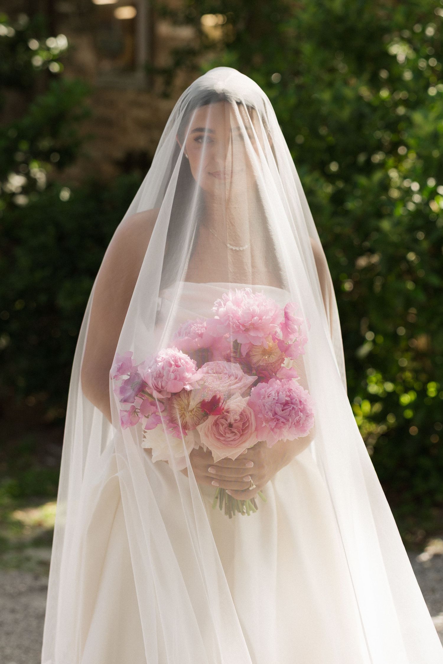 Bride and groom share their first kiss as husband and wife at Fountain of Youth in St. Augustine, Florida surrounded by white roses.