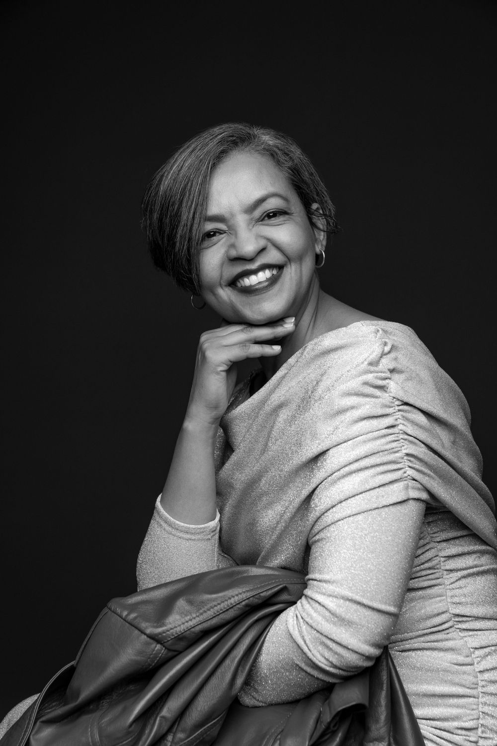 Professional black and white portrait showing joyful expression against dark background.