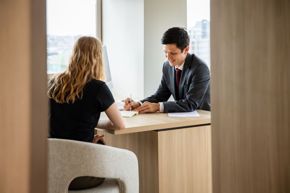 Business professionals meeting in modern office conference room with wood paneled walls and natural lighting.