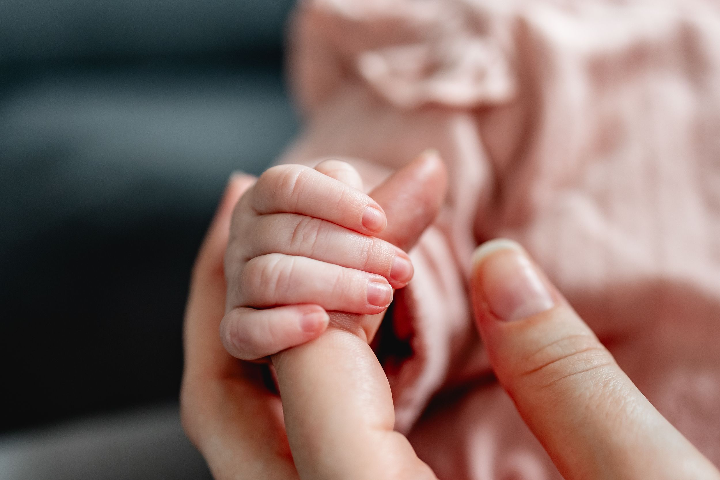 Close-up details of tiny baby hands and fingers in pink tones.