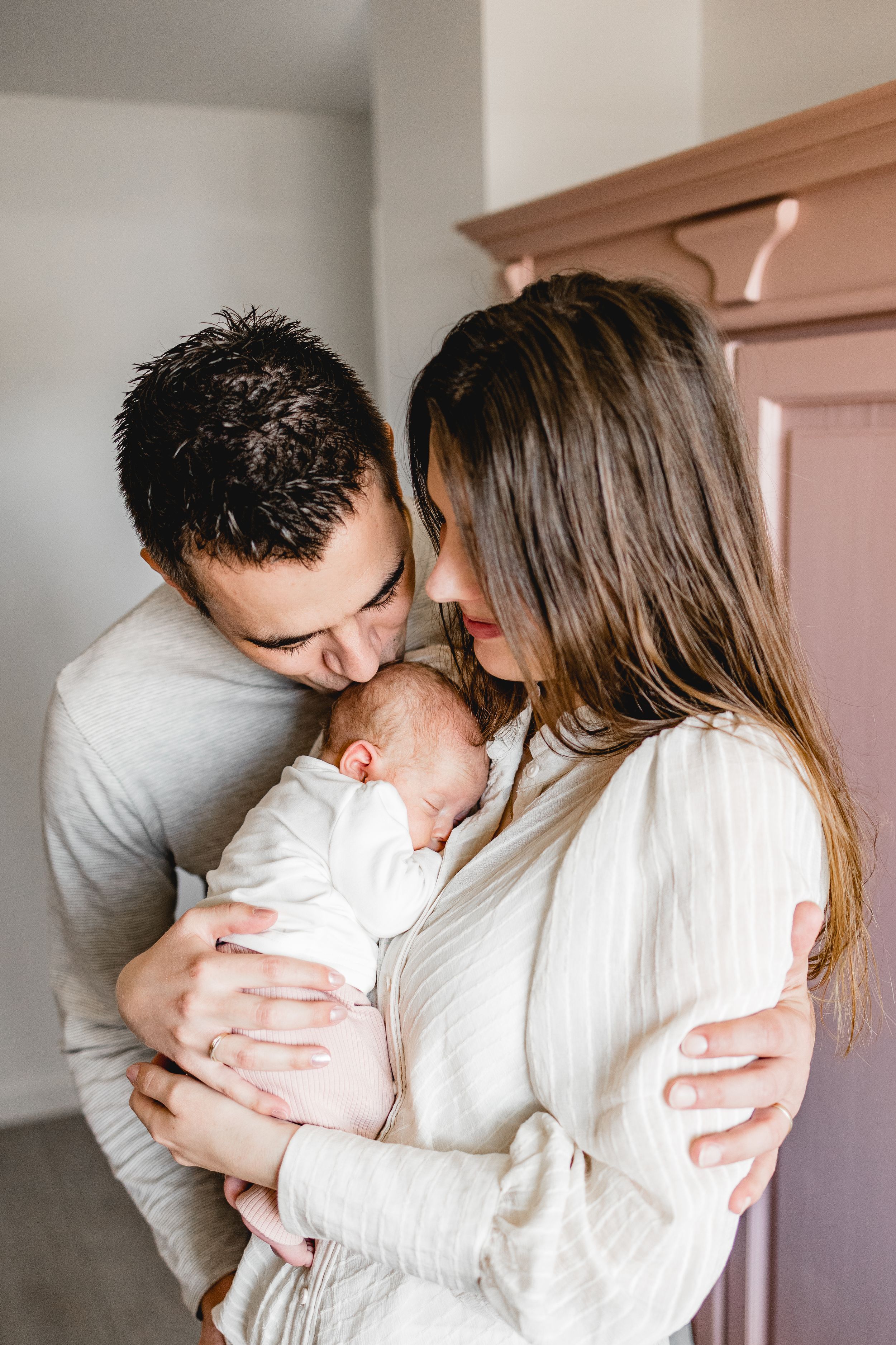 Tender moment shared with newborn baby in warm indoor setting.