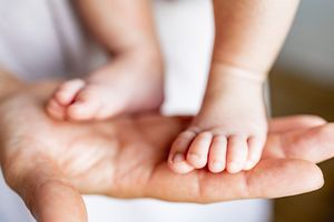 Close-up of tiny newborn baby toes and fingers against a white background.