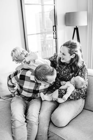 Black and white series of siblings sharing a playful moment on a couch.