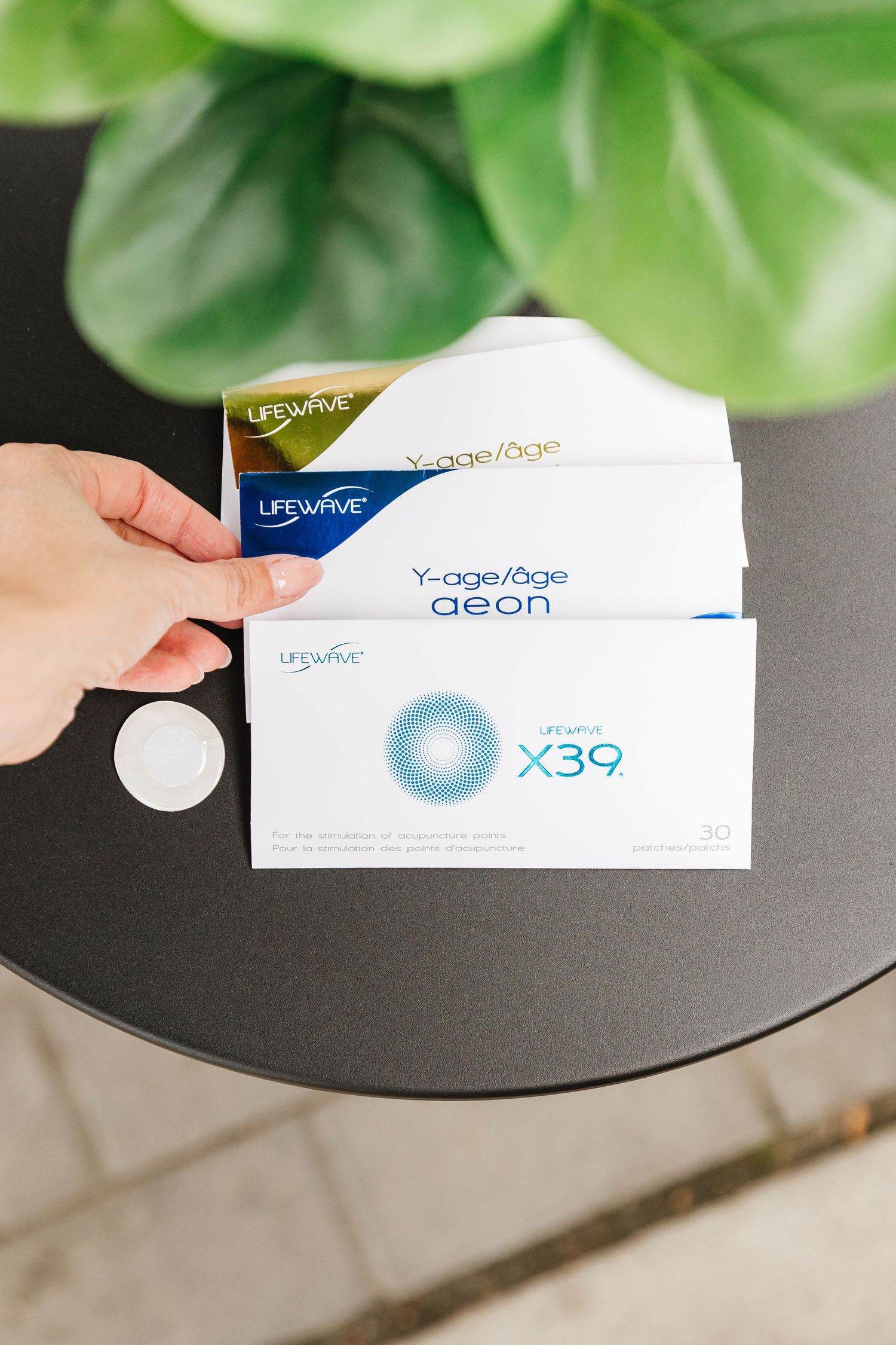 Contact lens boxes displayed on dark table with green plant leaves in background.