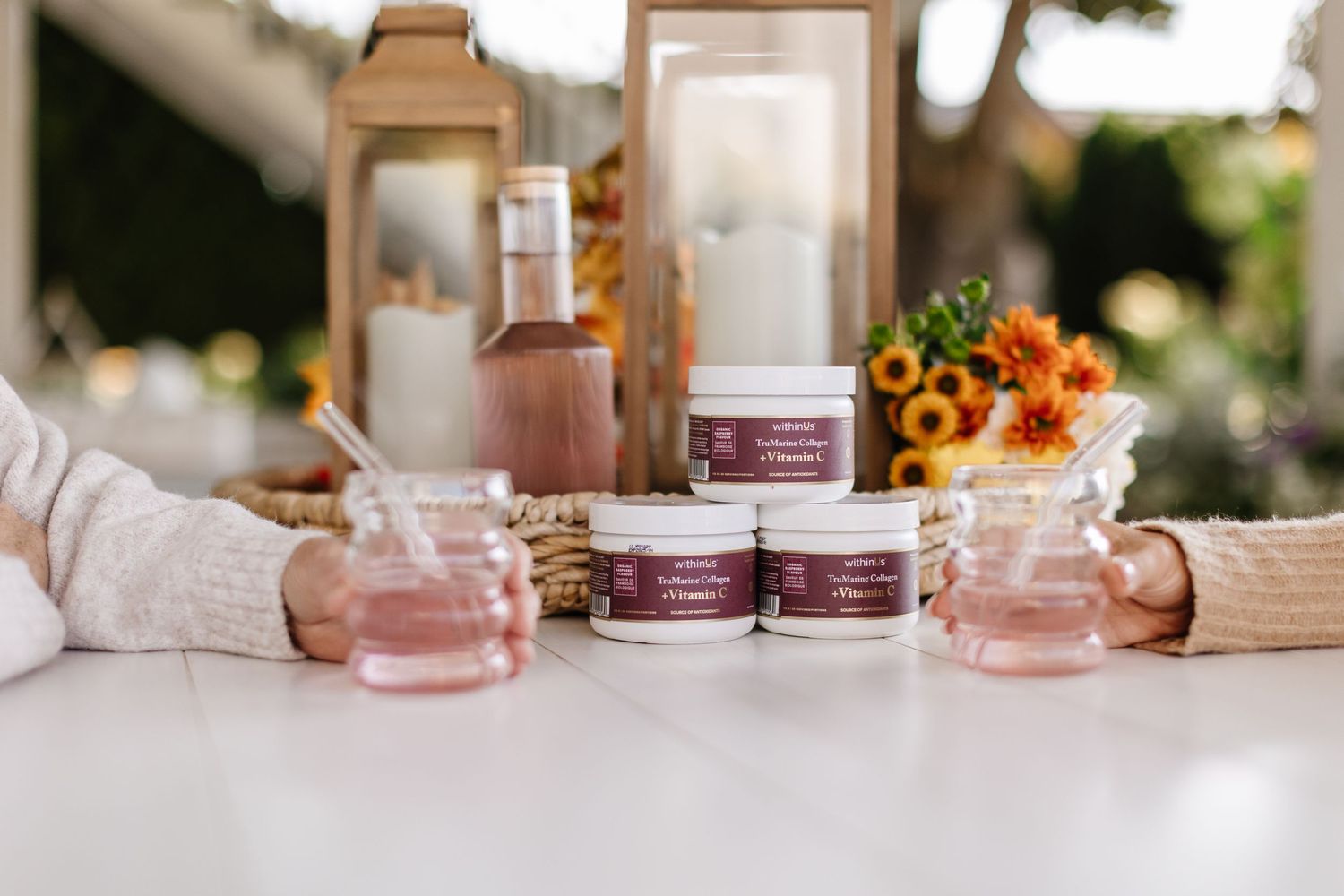 Pink beauty product containers arranged with sunflowers on a light surface.