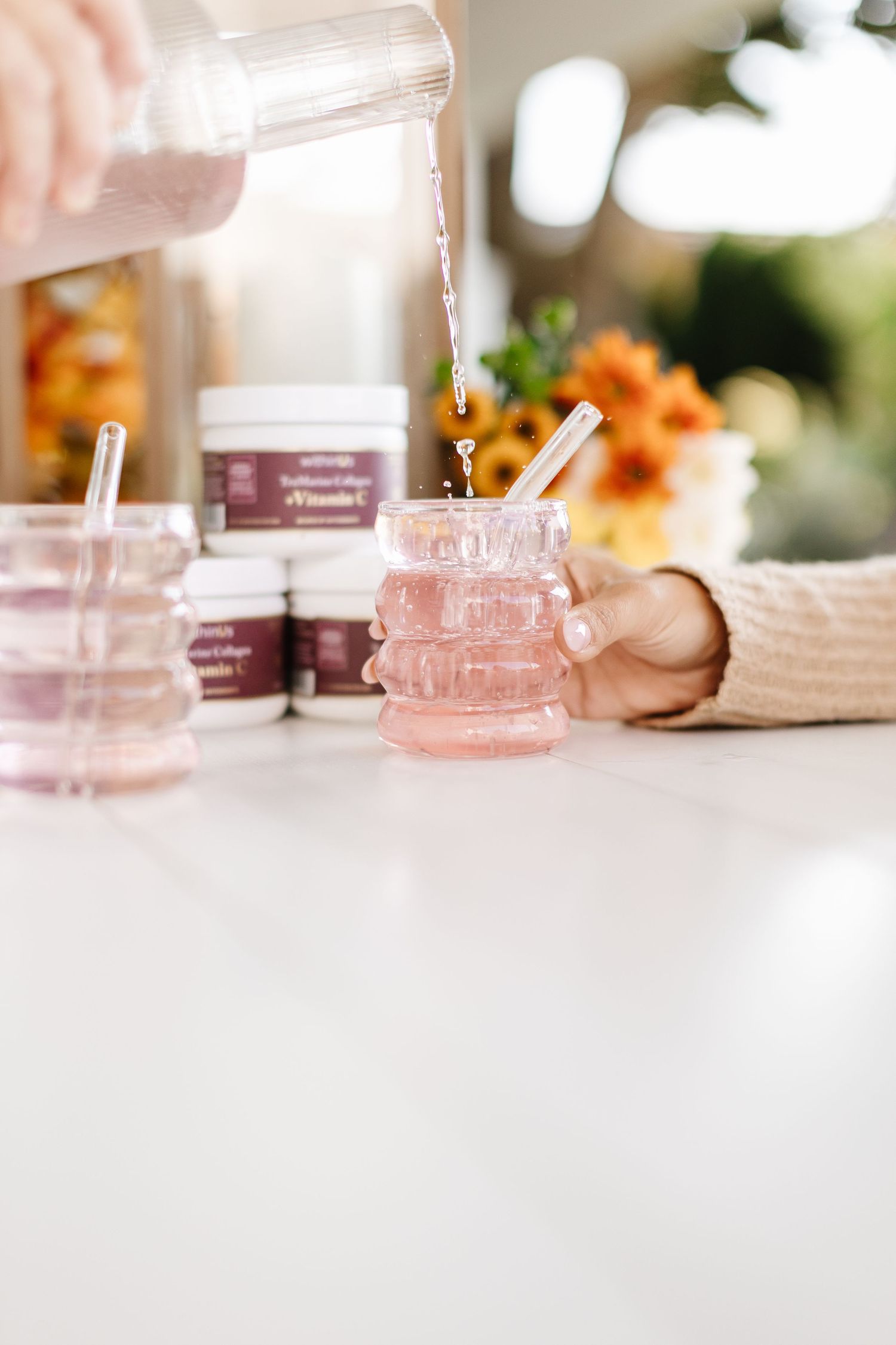Pink glass jars and beauty products displayed in soft natural lighting.