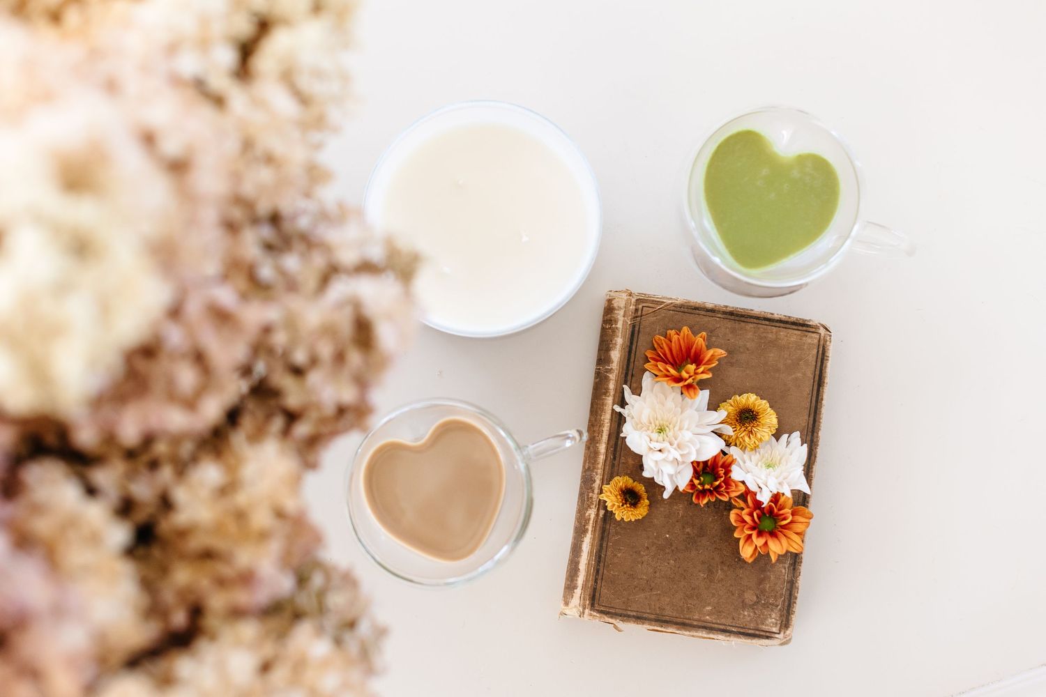 Autumn-themed flatlay with sunflowers, orange decor, and matcha tea on a white surface.