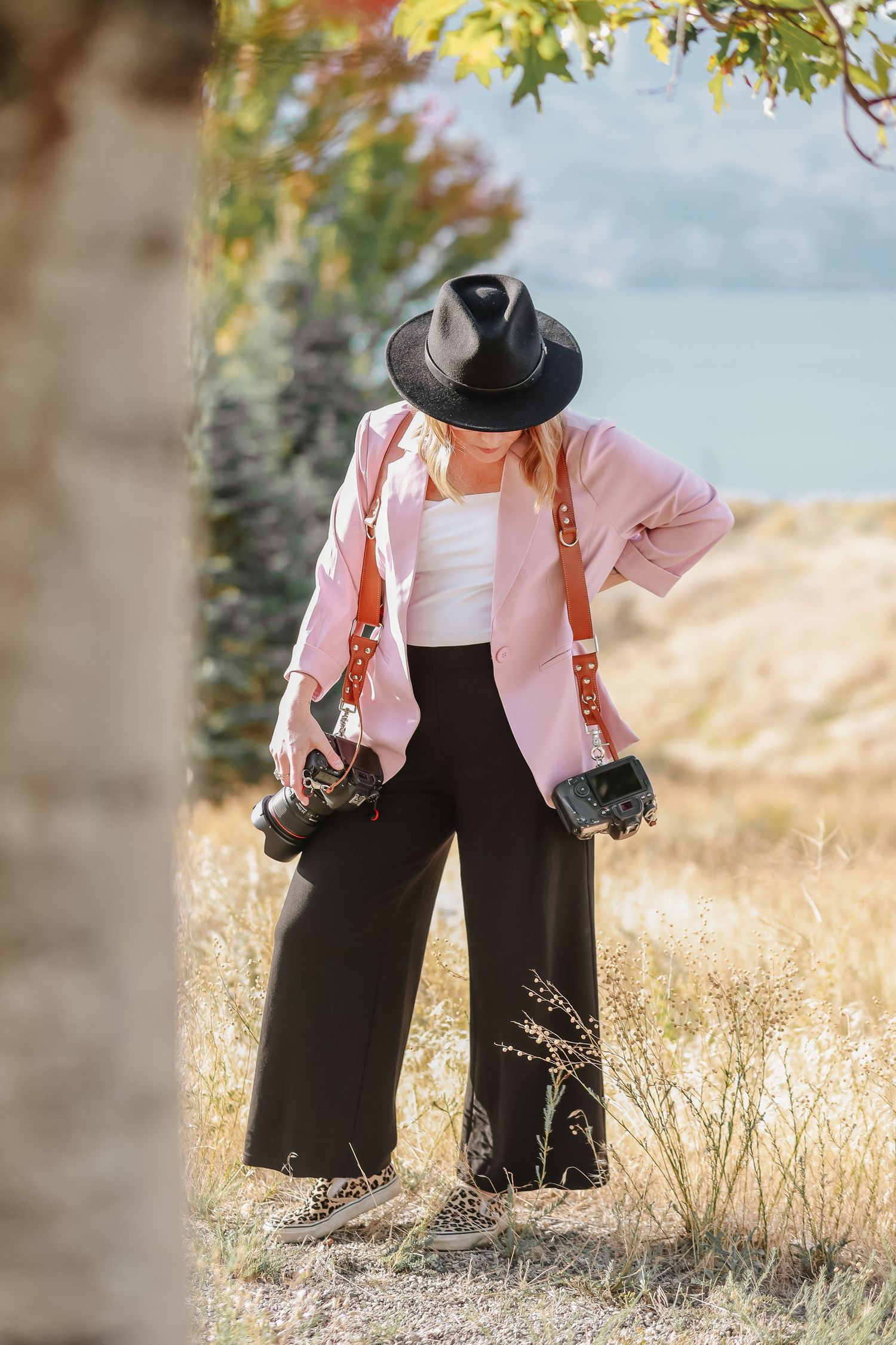 Side view of person in pink blazer and black pants standing in golden field.