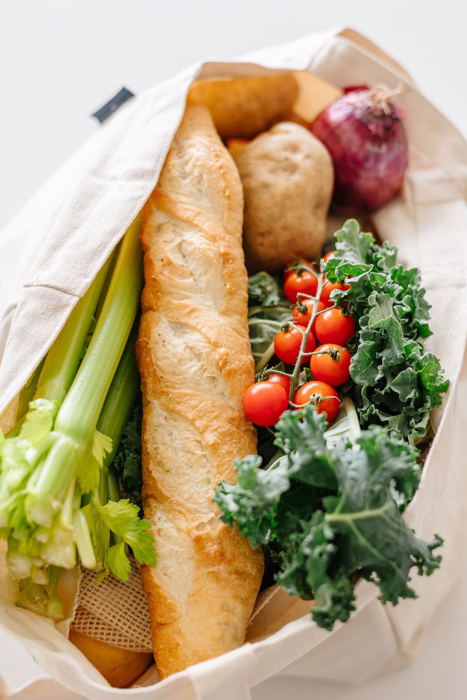 Fresh baguette sandwich with kale, tomatoes, and celery arranged in paper wrapping for food branding photography in Kelowna