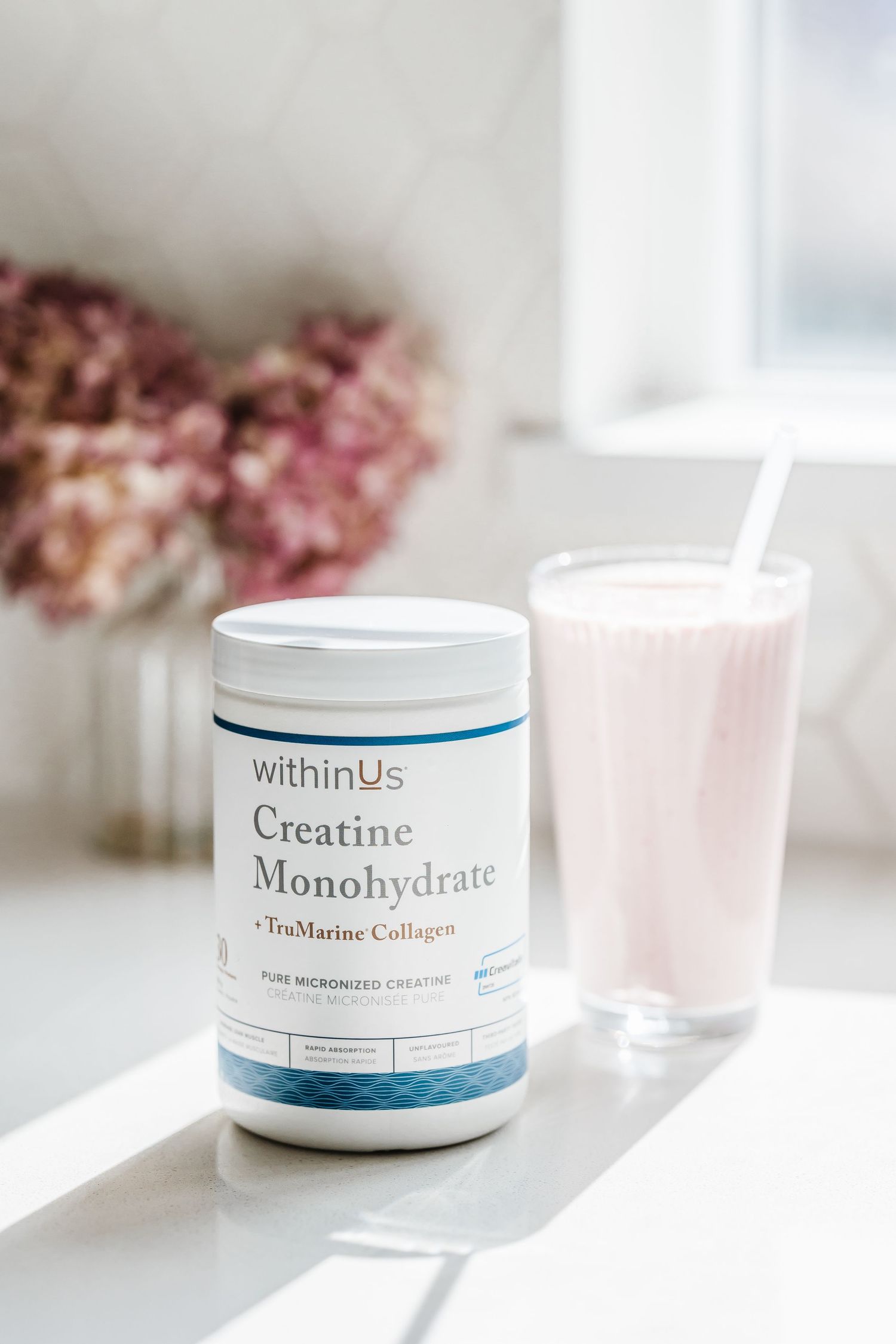 White supplement containers of WithinUs creatine and marine collagen arranged on a bright minimalist surface with soft lighting.