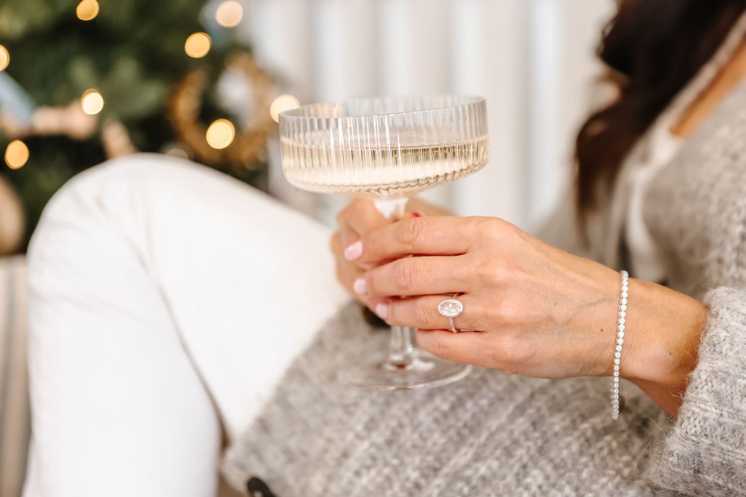 Elegant crystal champagne glass held by hand with diamond bracelet and engagement ring.