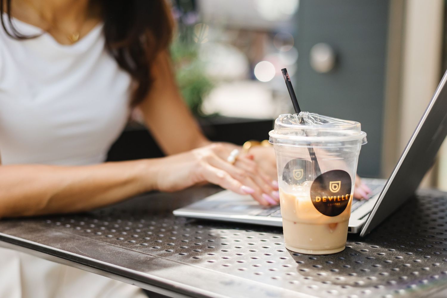 Person typing on laptop keyboard while sitting at desk with coffee cup nearby.