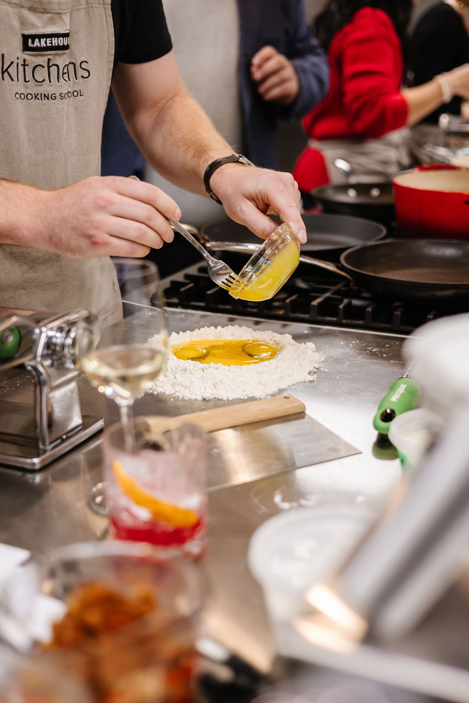 Hands preparing food on white counter in professional cooking class setting.
