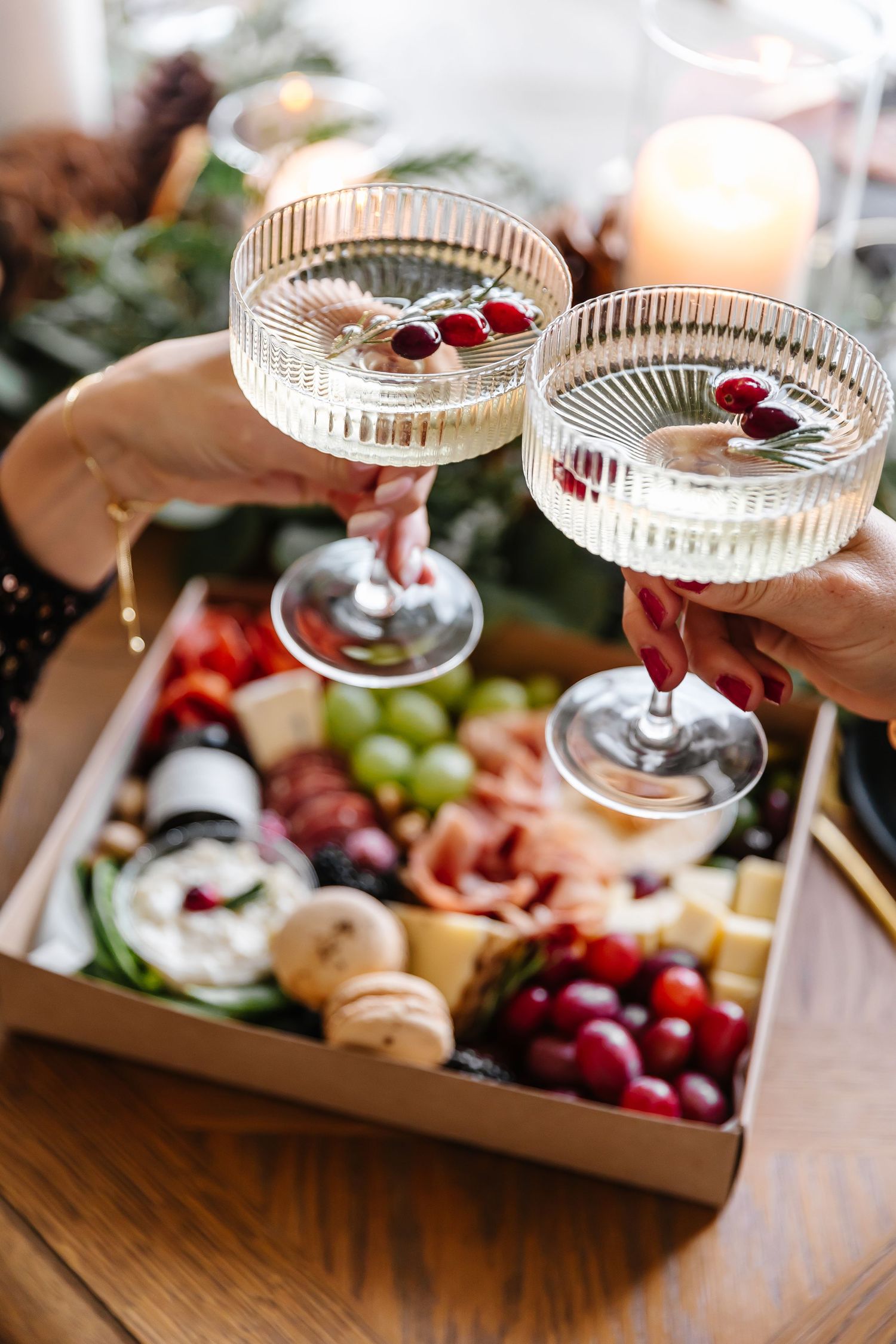 Charcuterie board with grapes and cheese alongside crystal champagne coupes.