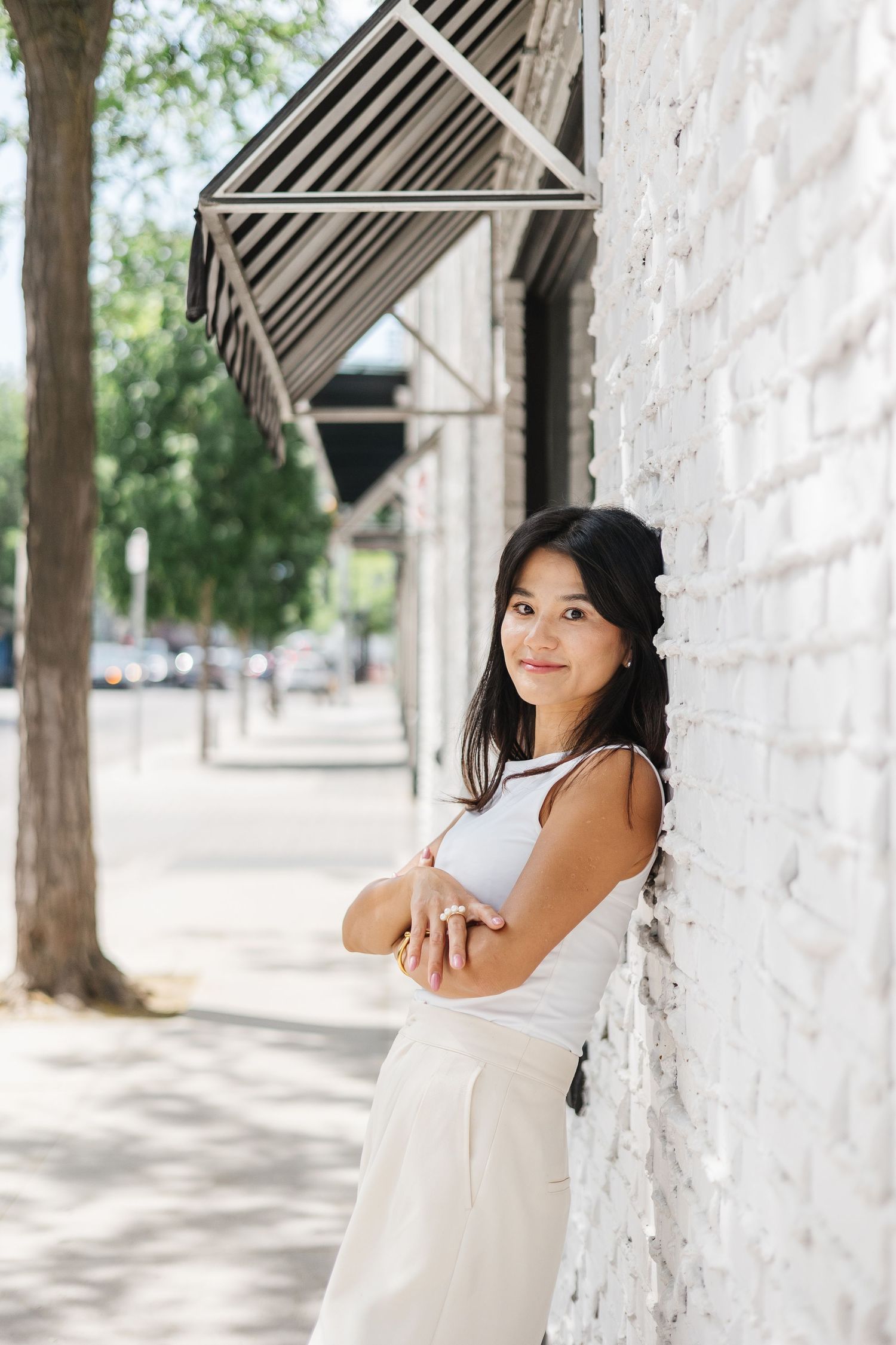 A bright outdoor setting with white brick walls and metal architectural details provides an urban backdrop.