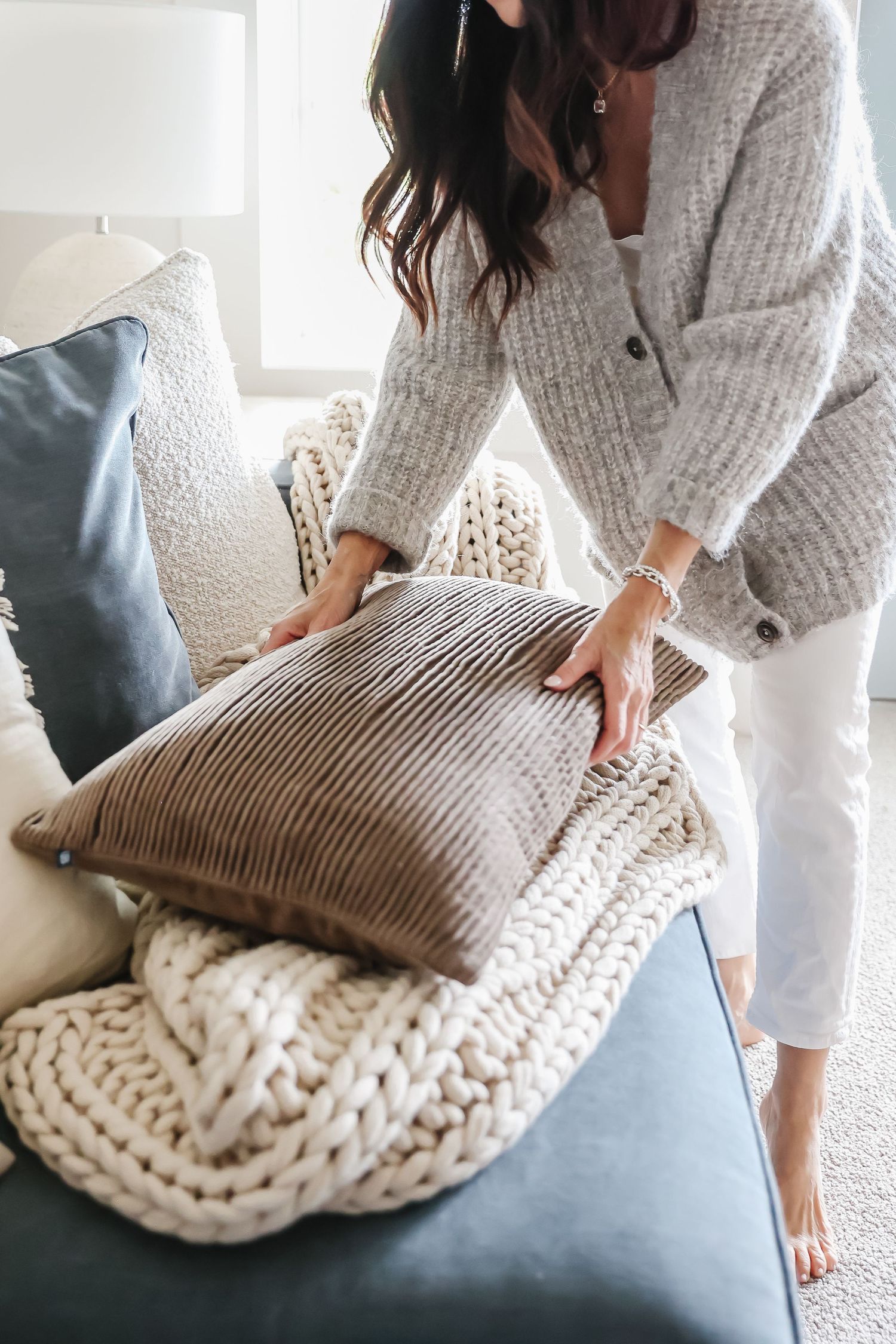 Cozy living room scene with knit throw pillows and grey cardigan against blue sofa.