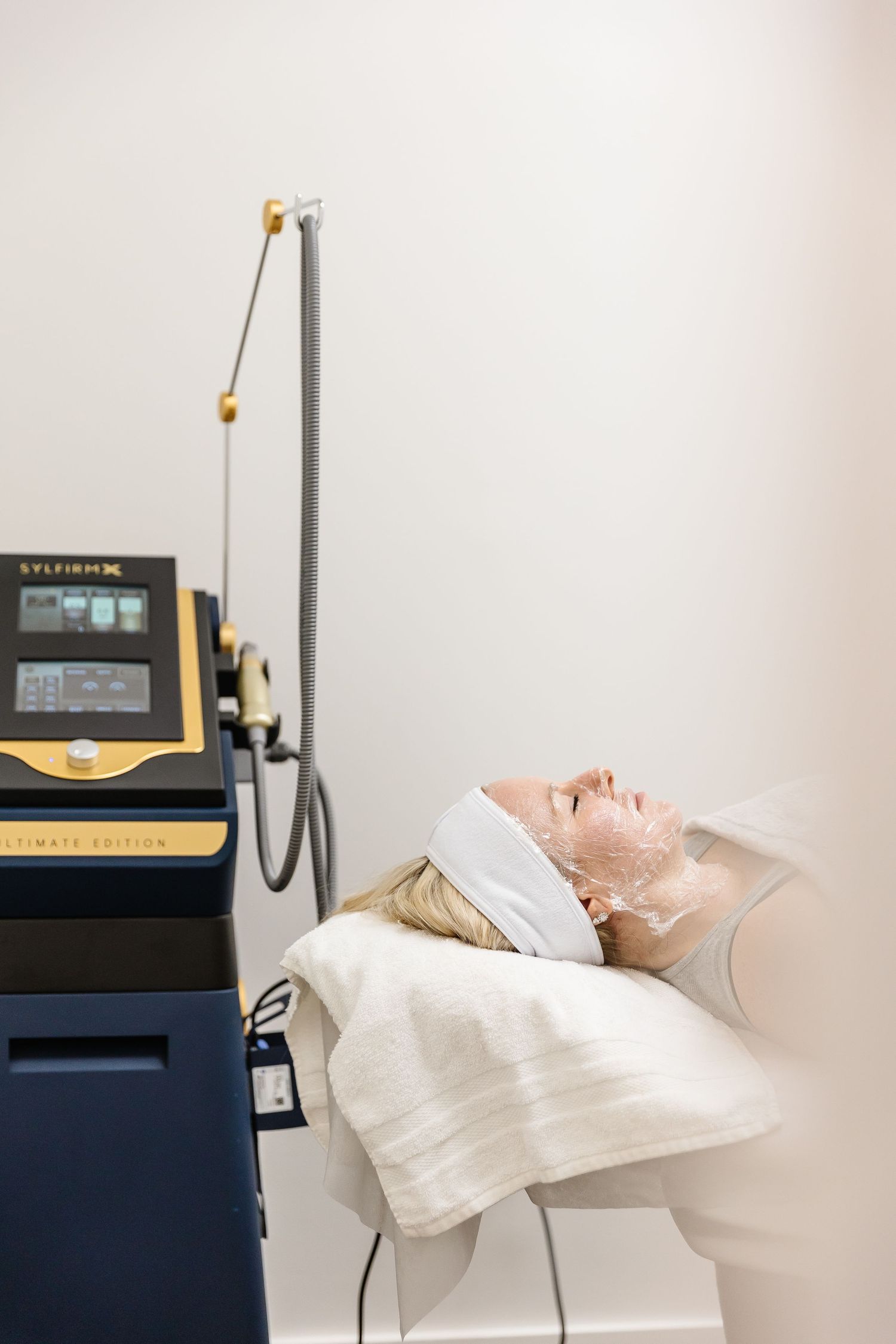 Medical patient lying on treatment table next to ultrasound therapy equipment during physical therapy session.