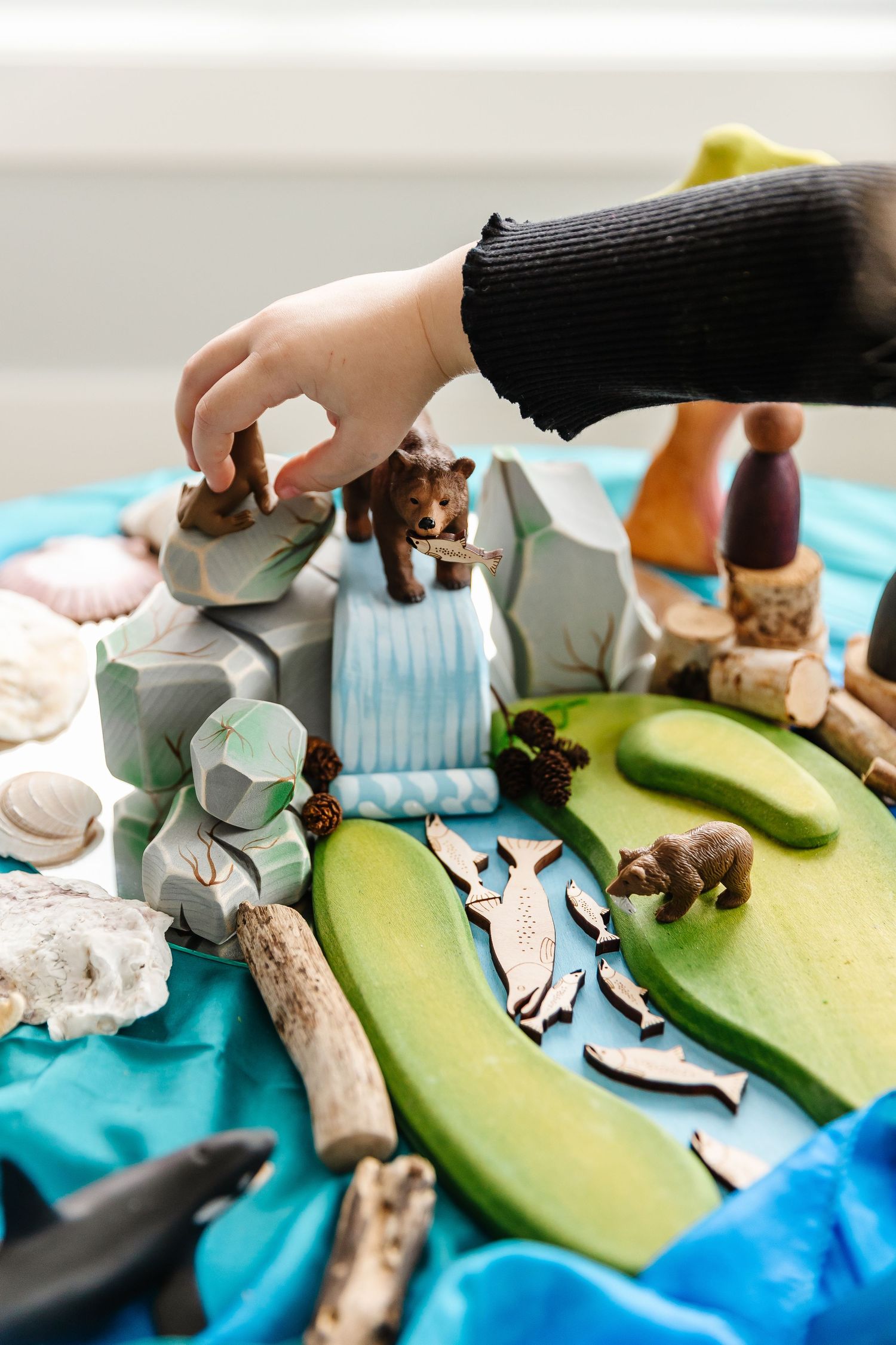Small animal figurines arranged on a blue and green play landscape.
