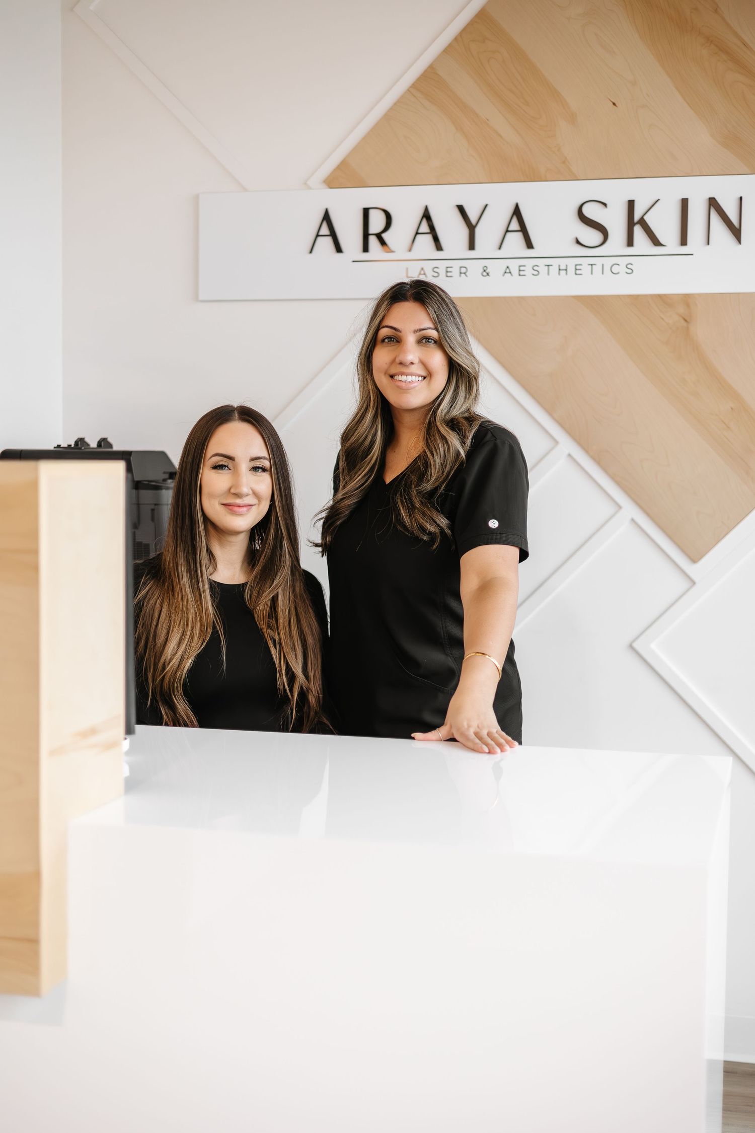 Professional branding photos of two women in a modern medical spa setting with light wood and white decor.