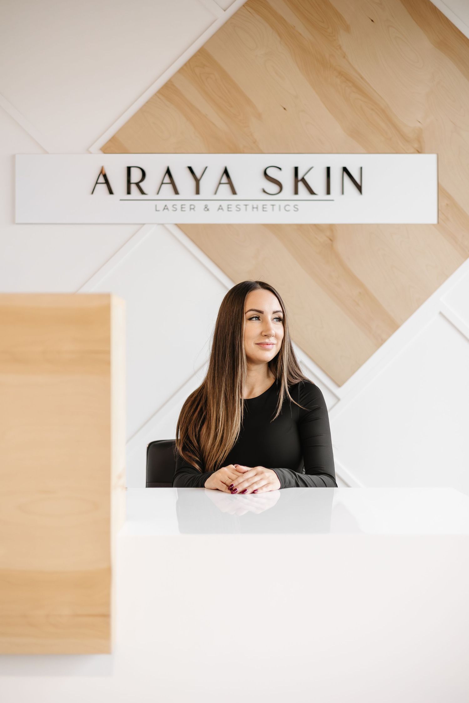 Modern beauty salon interior with Araya Skin signage and geometric wood wall design in warm neutral tones.