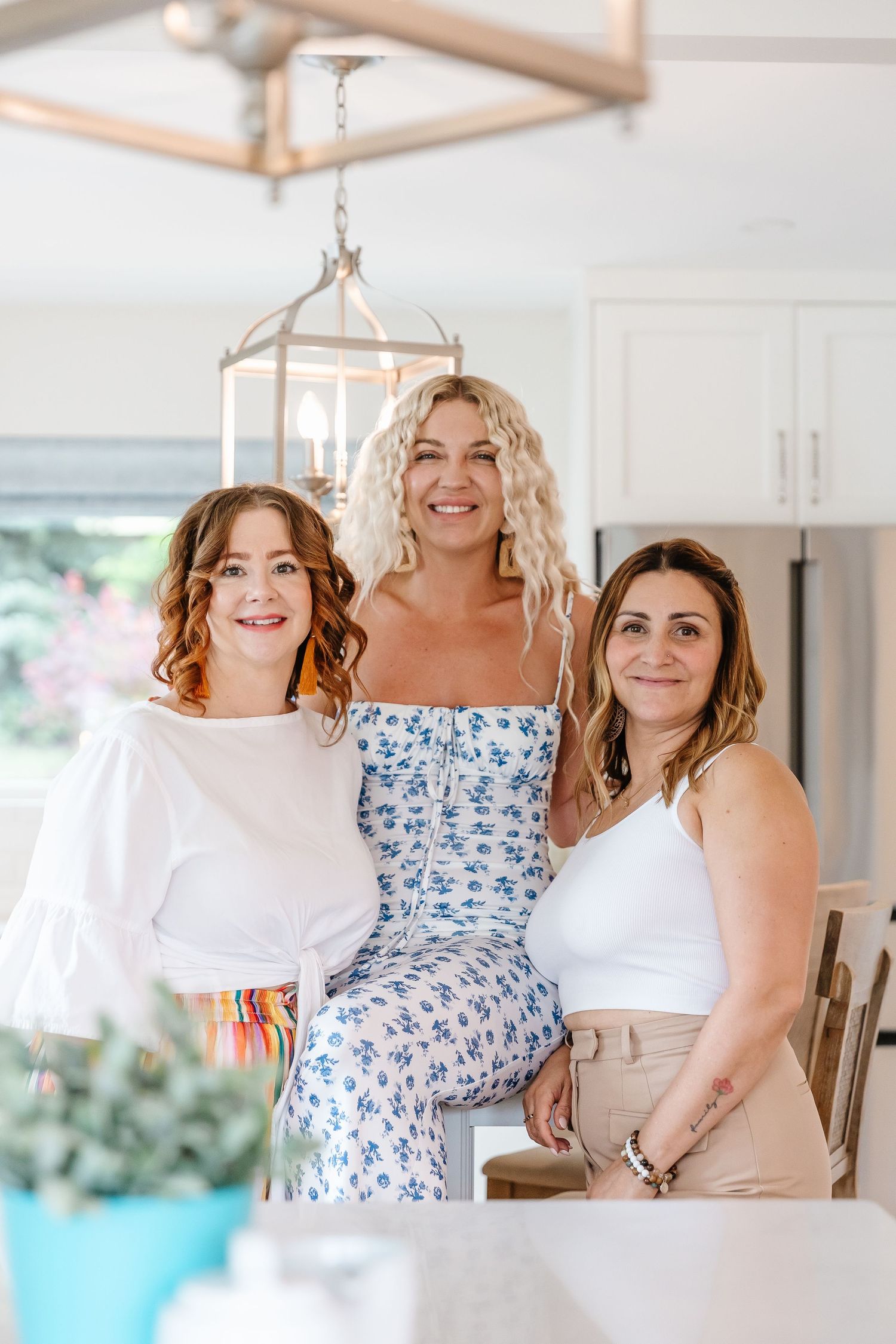 Group gathering in a bright modern kitchen with white decor and natural lighting.