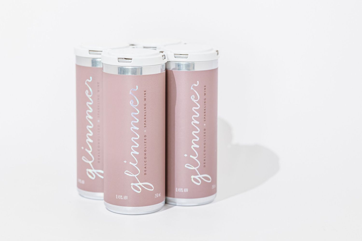 Pink aluminum cans of skincare or beauty products arranged in a minimalist composition against a white background.