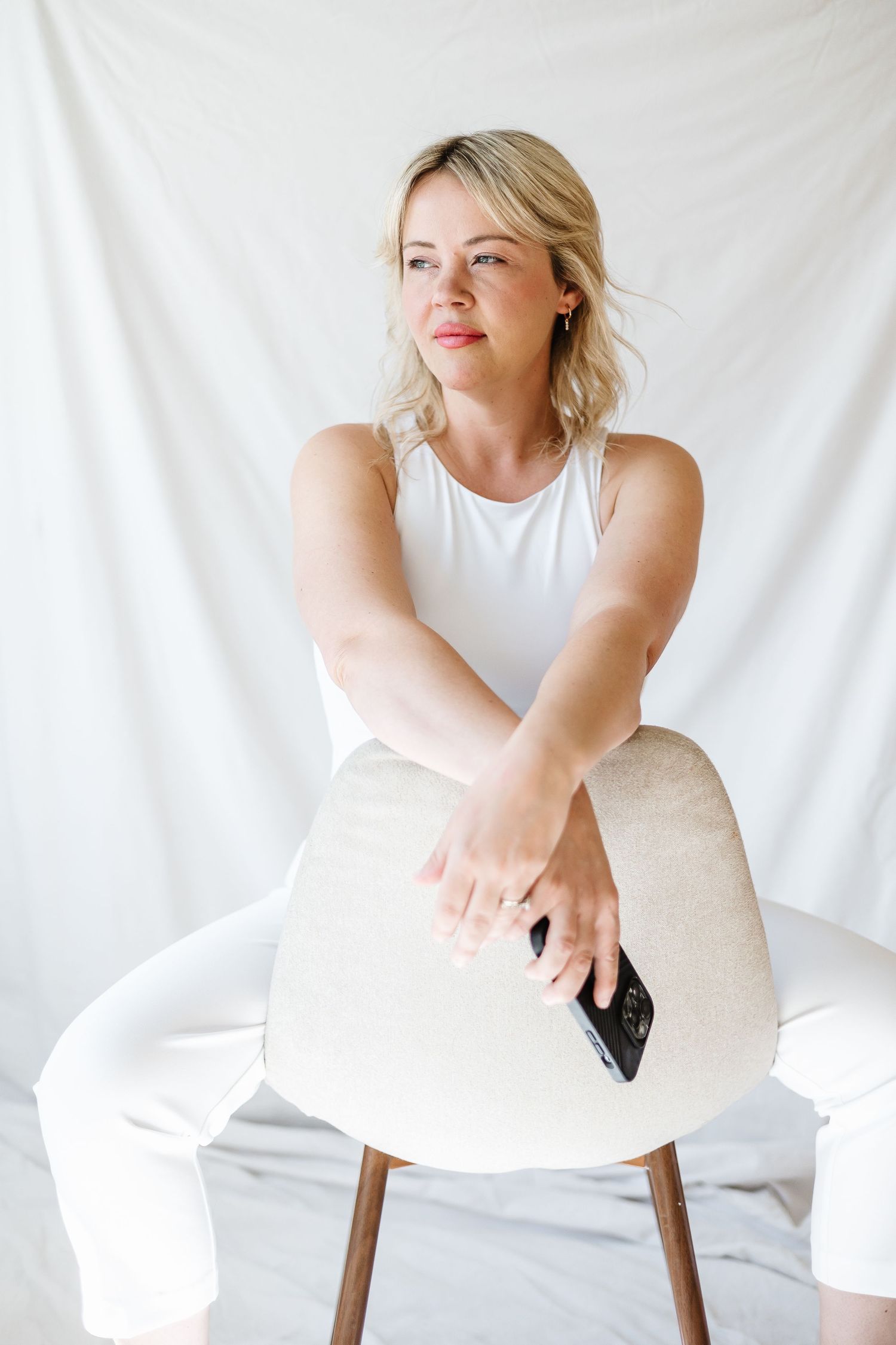 Lifestyle portrait session with white backdrop and modern chair styling.