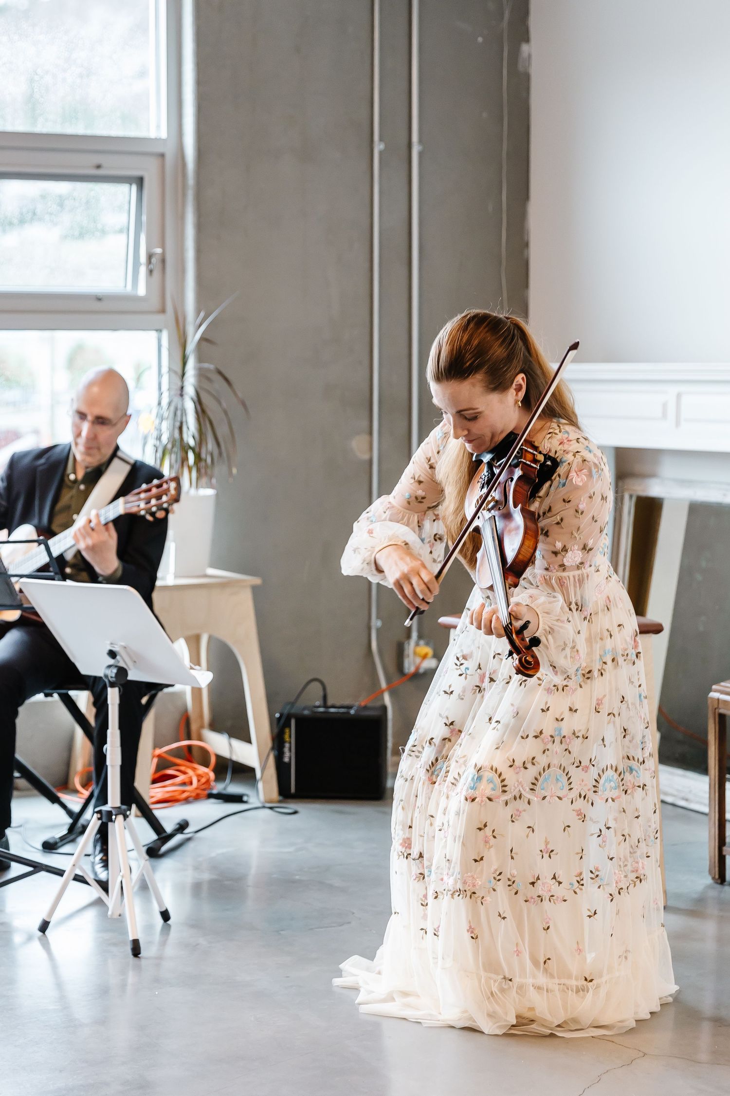 Musicians rehearsing in modern industrial space with concrete walls and natural light.