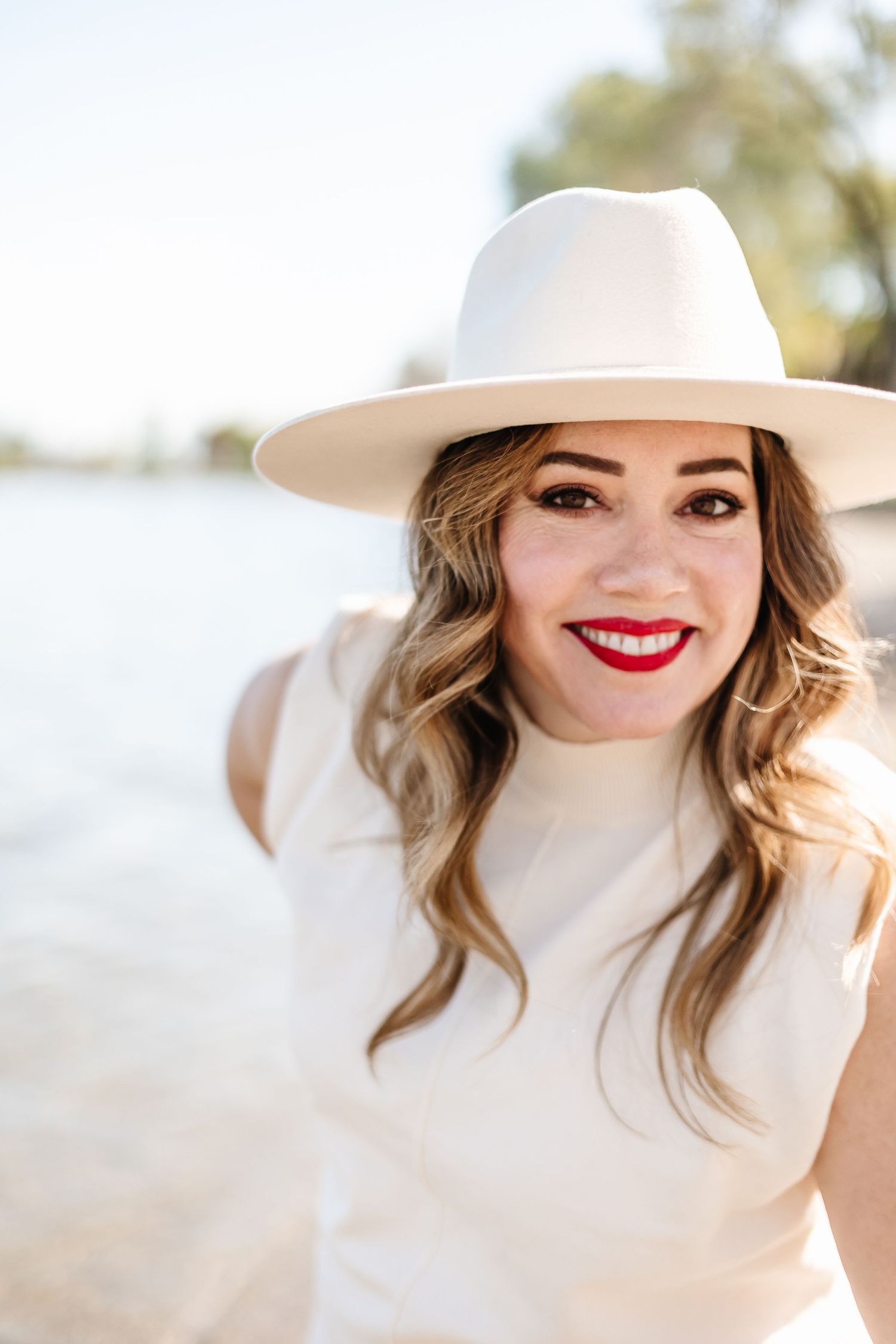 White sun hat and elegant attire against a bright outdoor background.