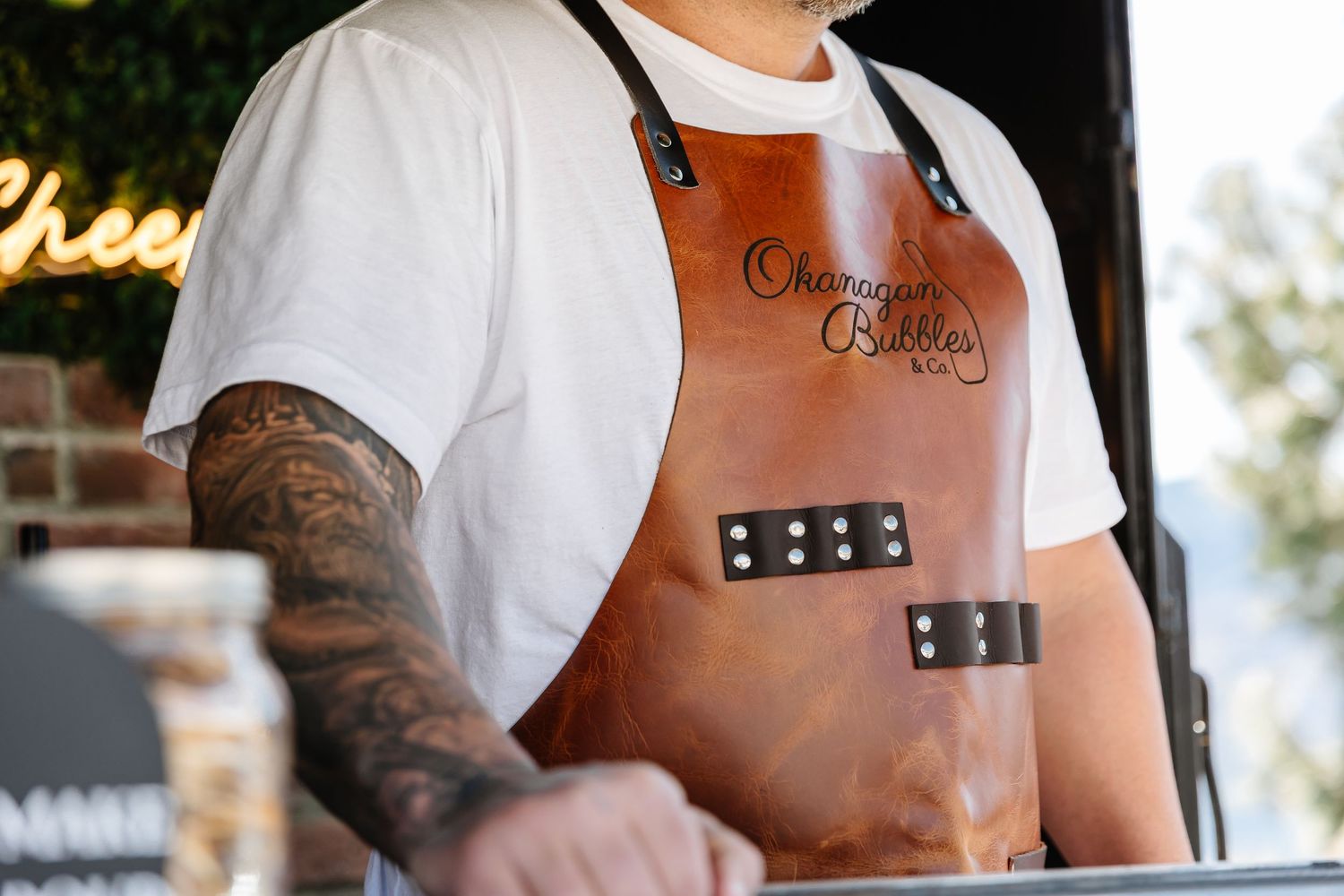 Close-up view of a craftsperson wearing a brown leather apron with black straps while working.