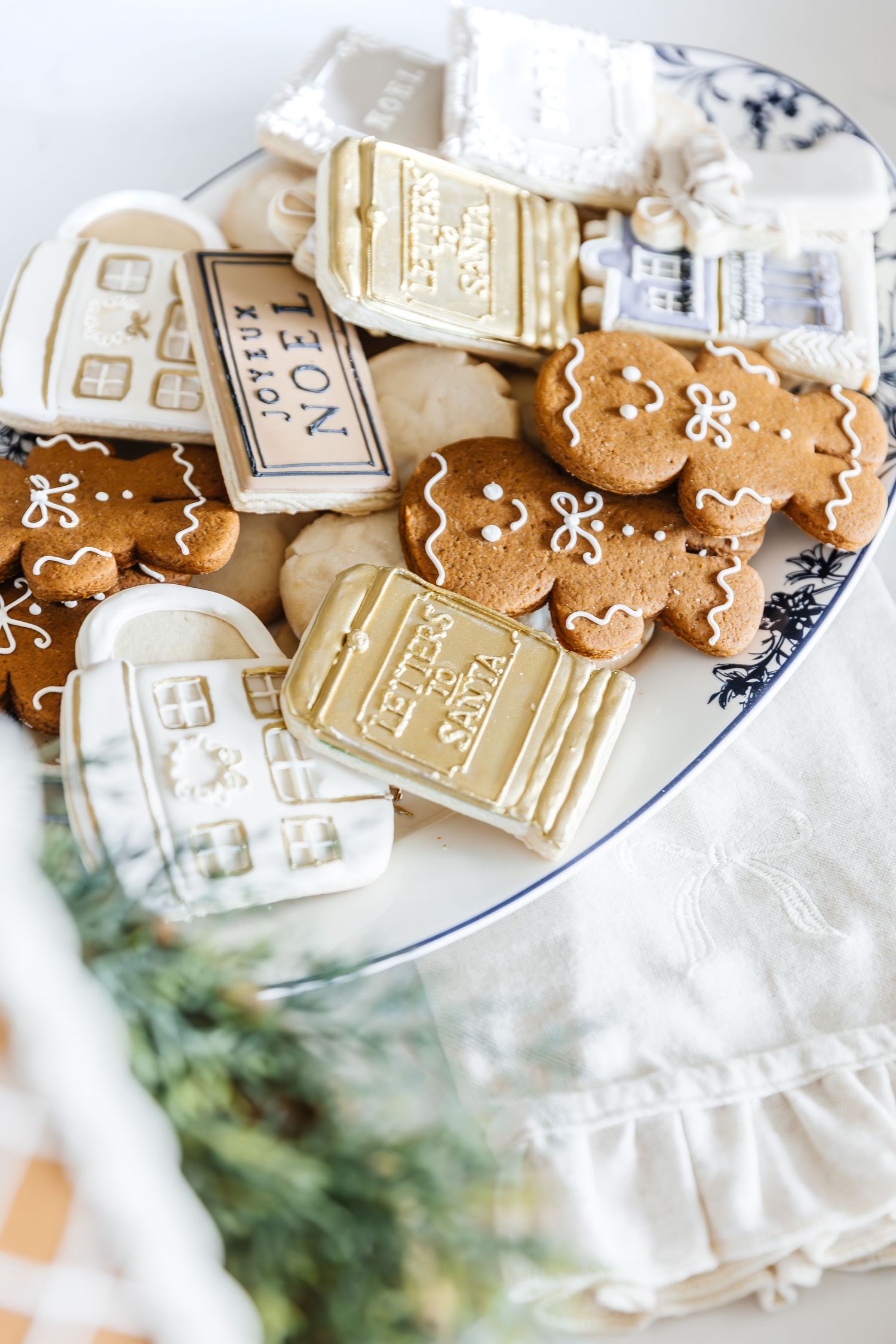 Gingerbread cookies and white decorative houses arranged on a blue and white patterned plate with festive holiday decor.