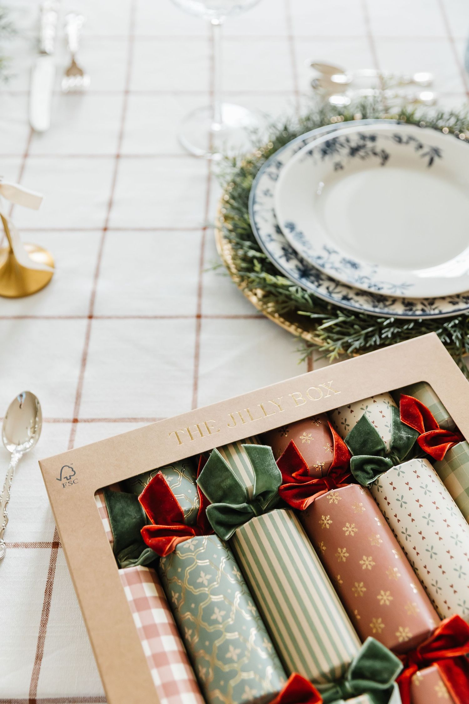 Festive Christmas crackers wrapped in patterned paper with red bows displayed in a kraft paper box.
