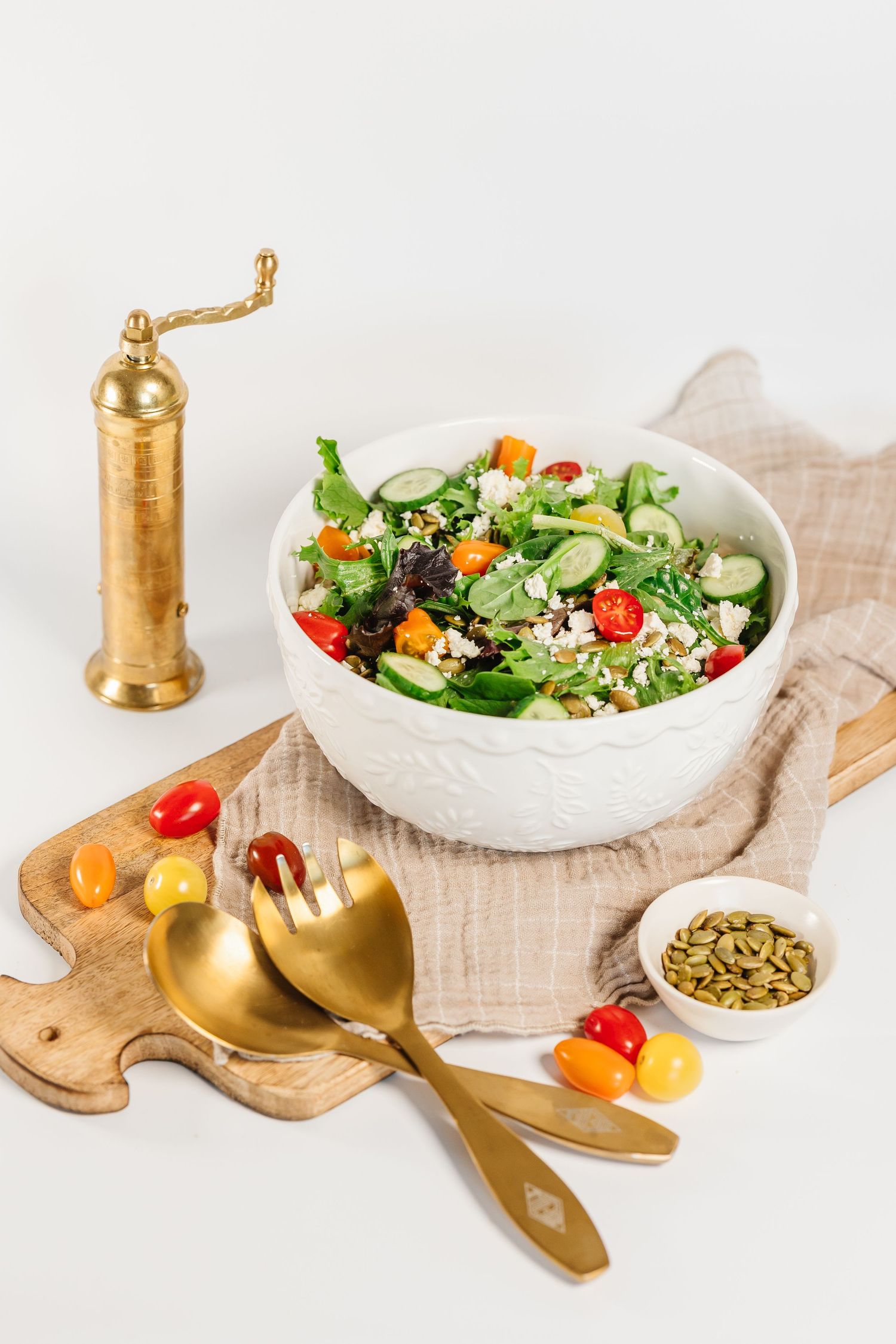 Fresh garden salad in white bowl with golden utensils on white background for a branding photography photoshoot in Kelowna, BC