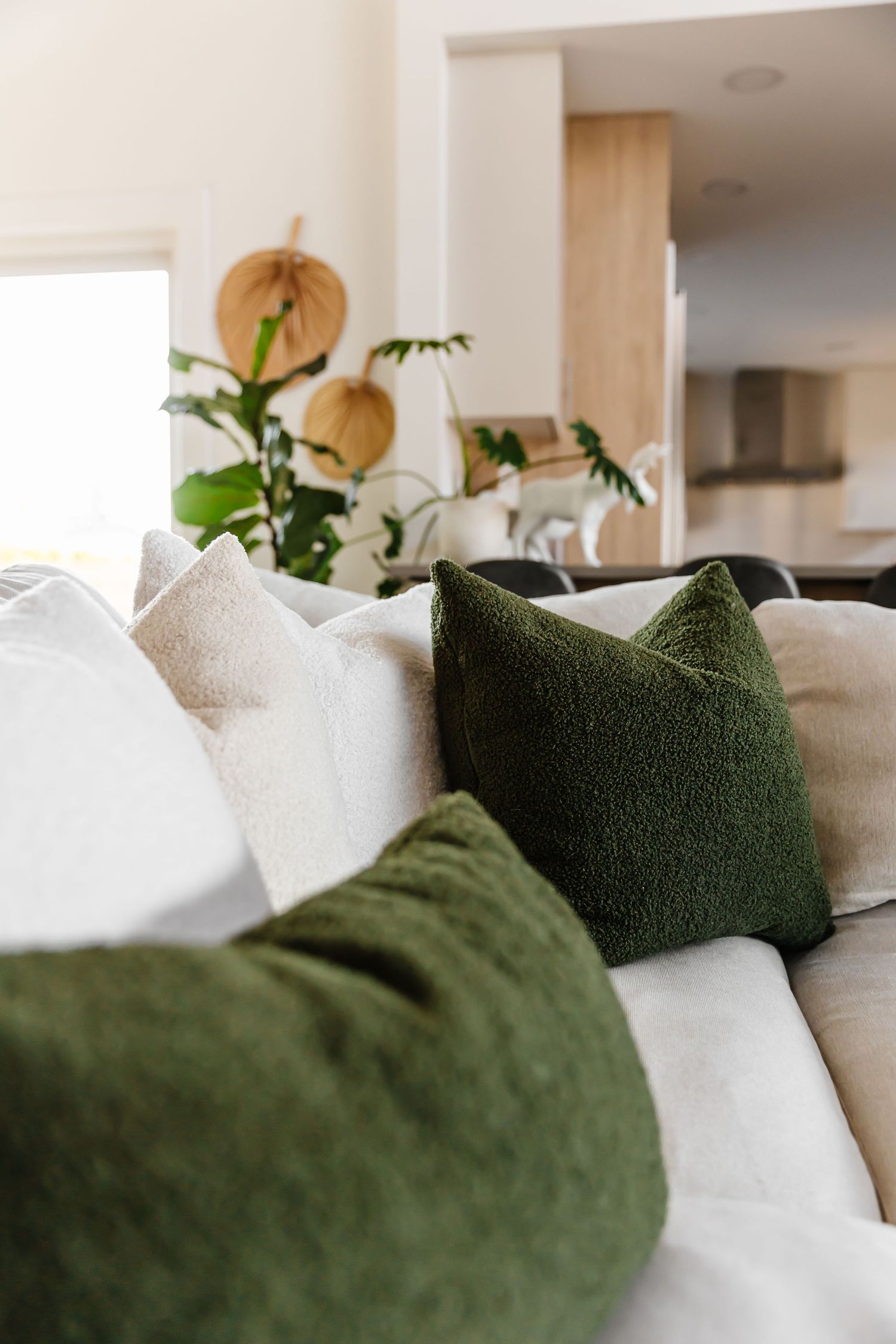 Close-up of green and white throw pillows on a couch with natural lighting.