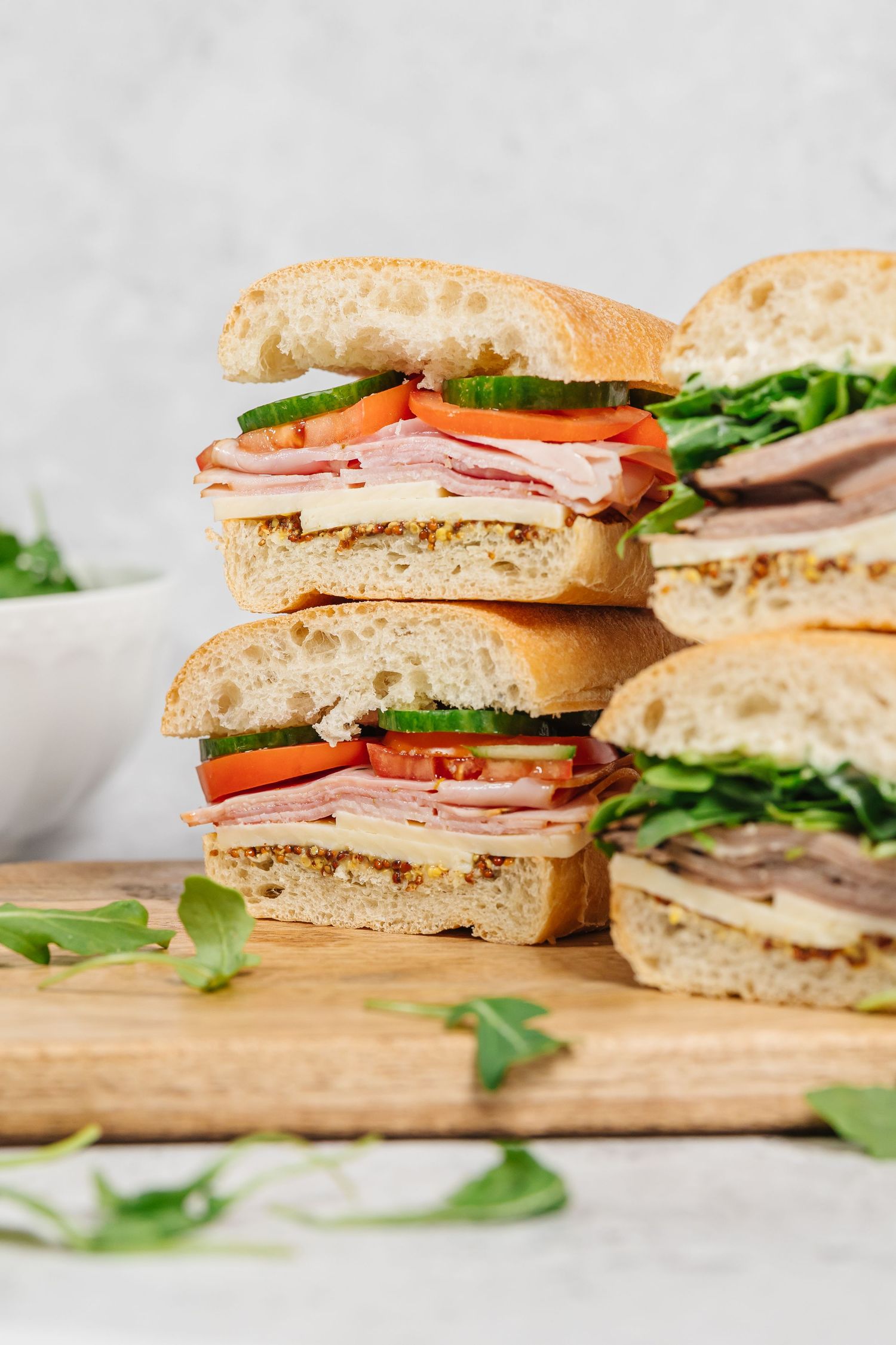 Close-up of layered turkey club sandwiches with lettuce and tomato on rustic wooden boards for a branding photoshoot in Kelowna, BC
