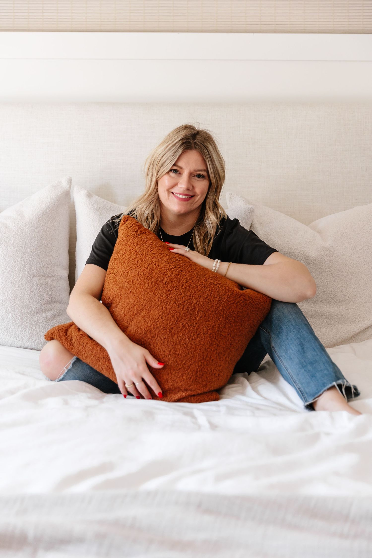 Cozy bedroom scene with rust-colored pillows and white bedding.