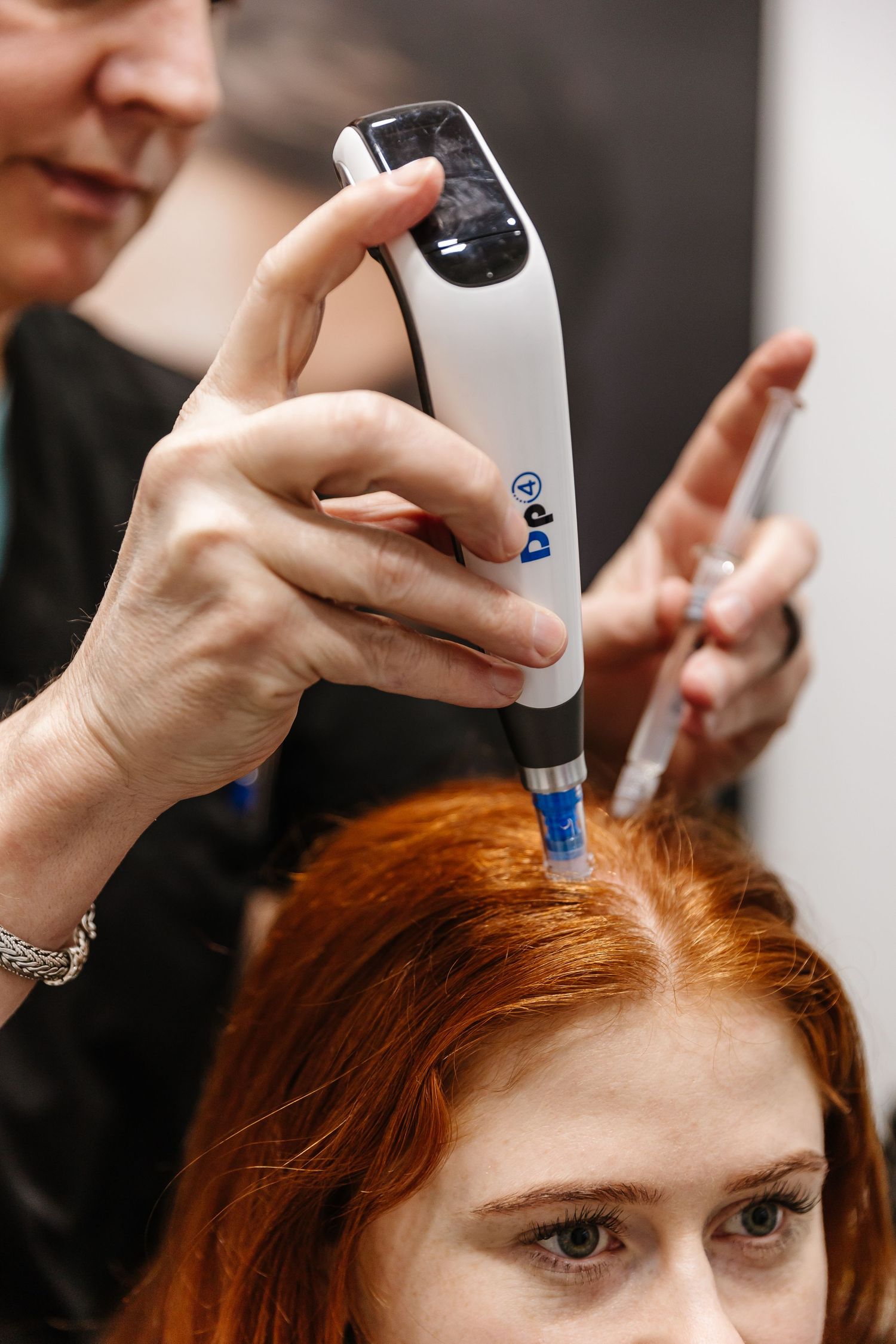 Professional hairstylist using a hair color applicator tool on red hair during a salon treatment.