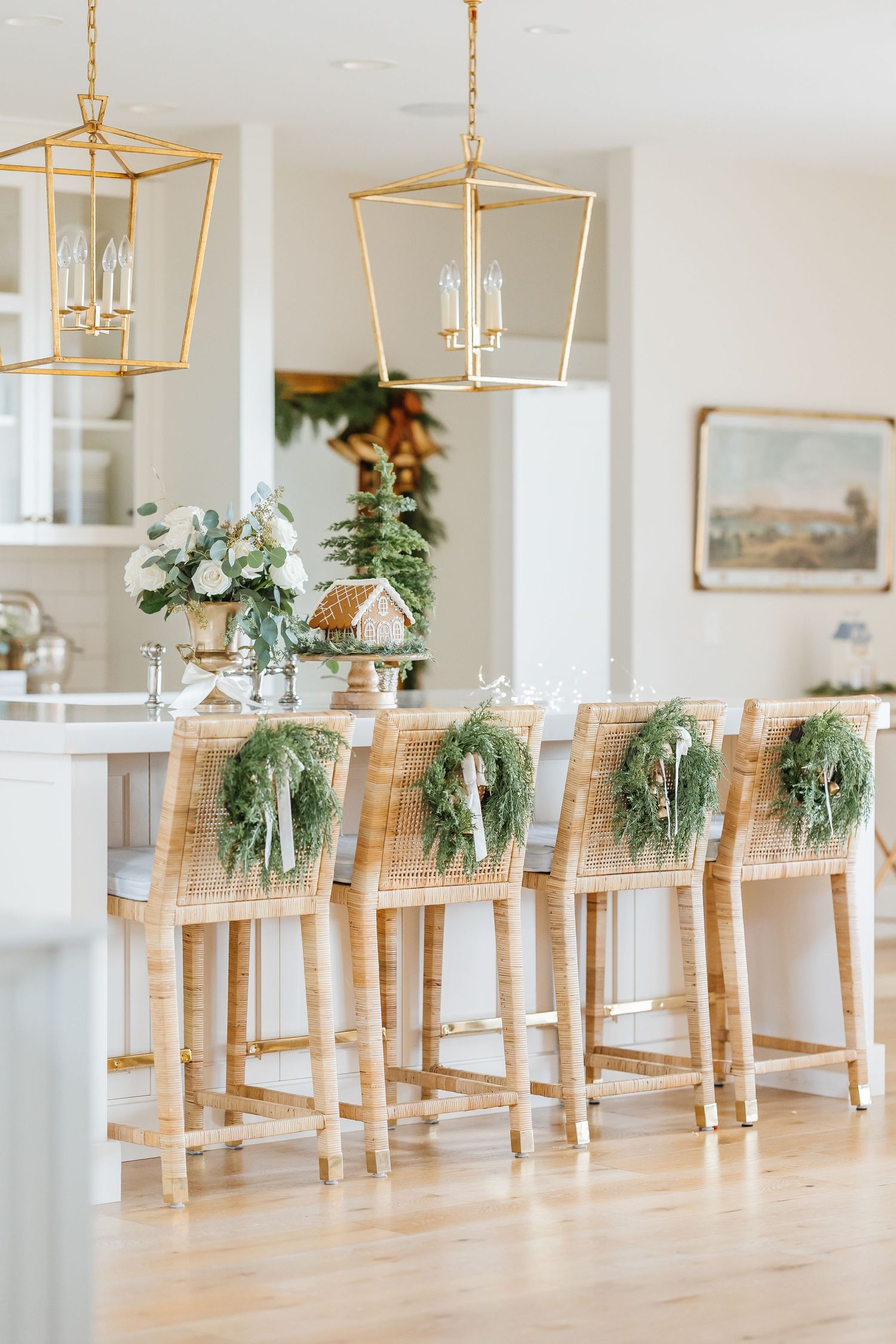 Elegant dining room with gold lantern pendants and holiday greenery wreaths adorning wooden barstools.