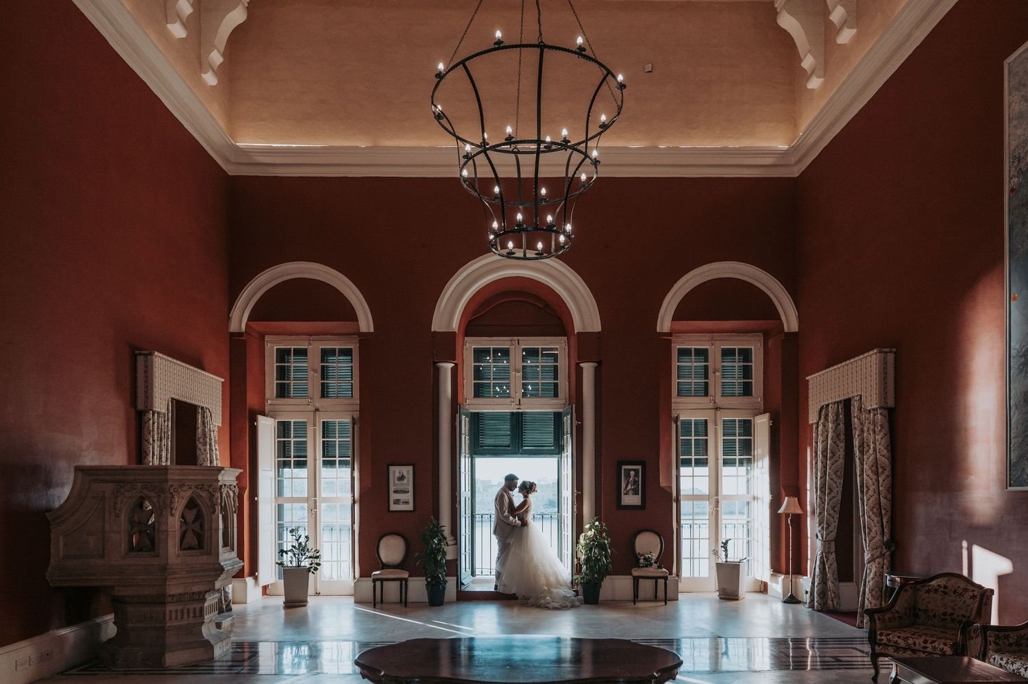 Couple dancing by large windows in an elegant indoor setting.