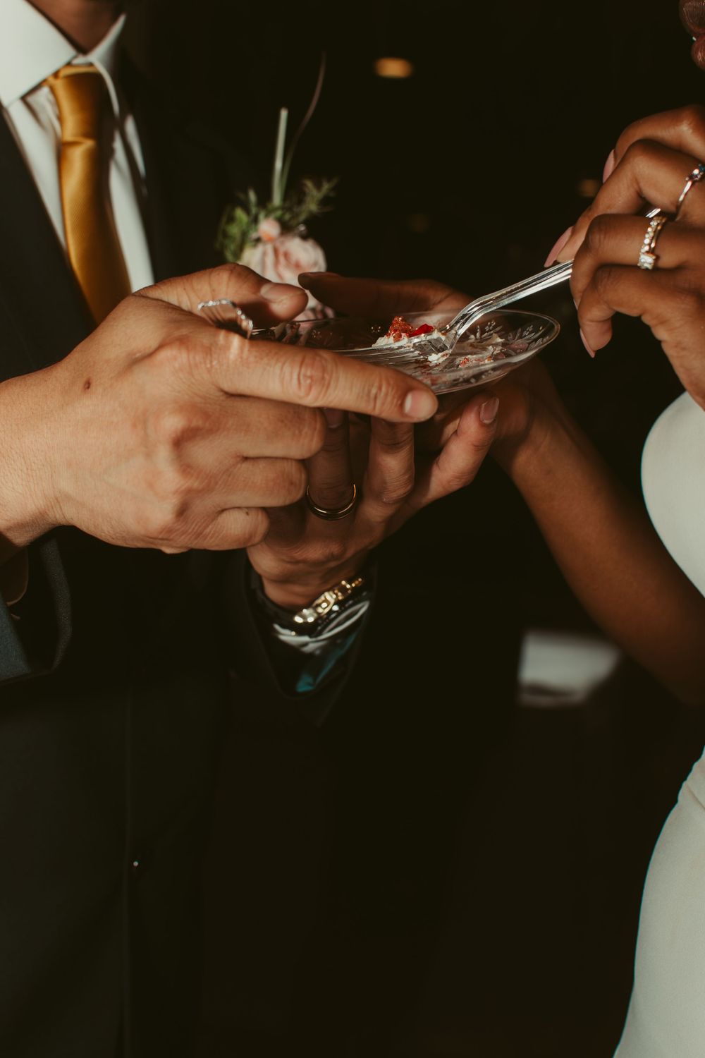 Close-up view of hands exchanging wedding rings during an intimate ceremony.