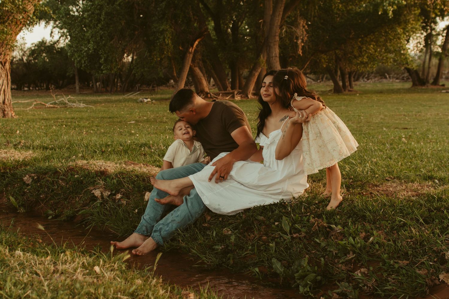 Family enjoying playful moment together on grassy field at sunset.