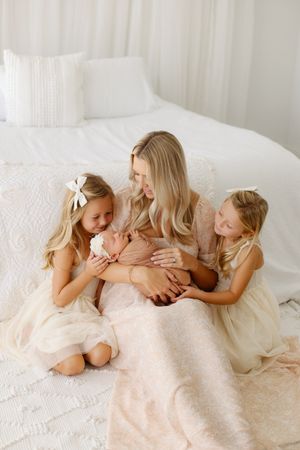 mom and sisters snuggling baby girl
