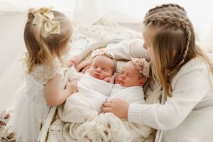 sisters looking at newborn twin girls